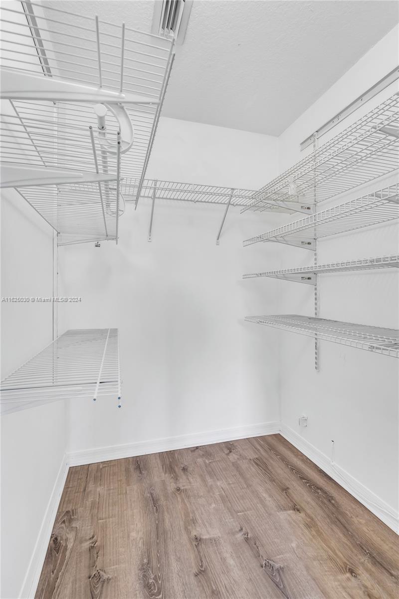 Walk-in closet with white wire shelving and wood-look plank flooring.