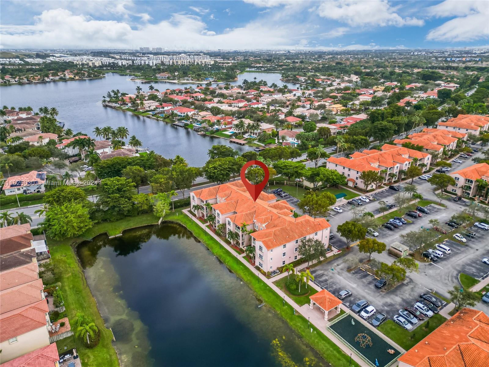 Aerial view of a lakeside condominium community, with a red pin marking an orange-roofed building.