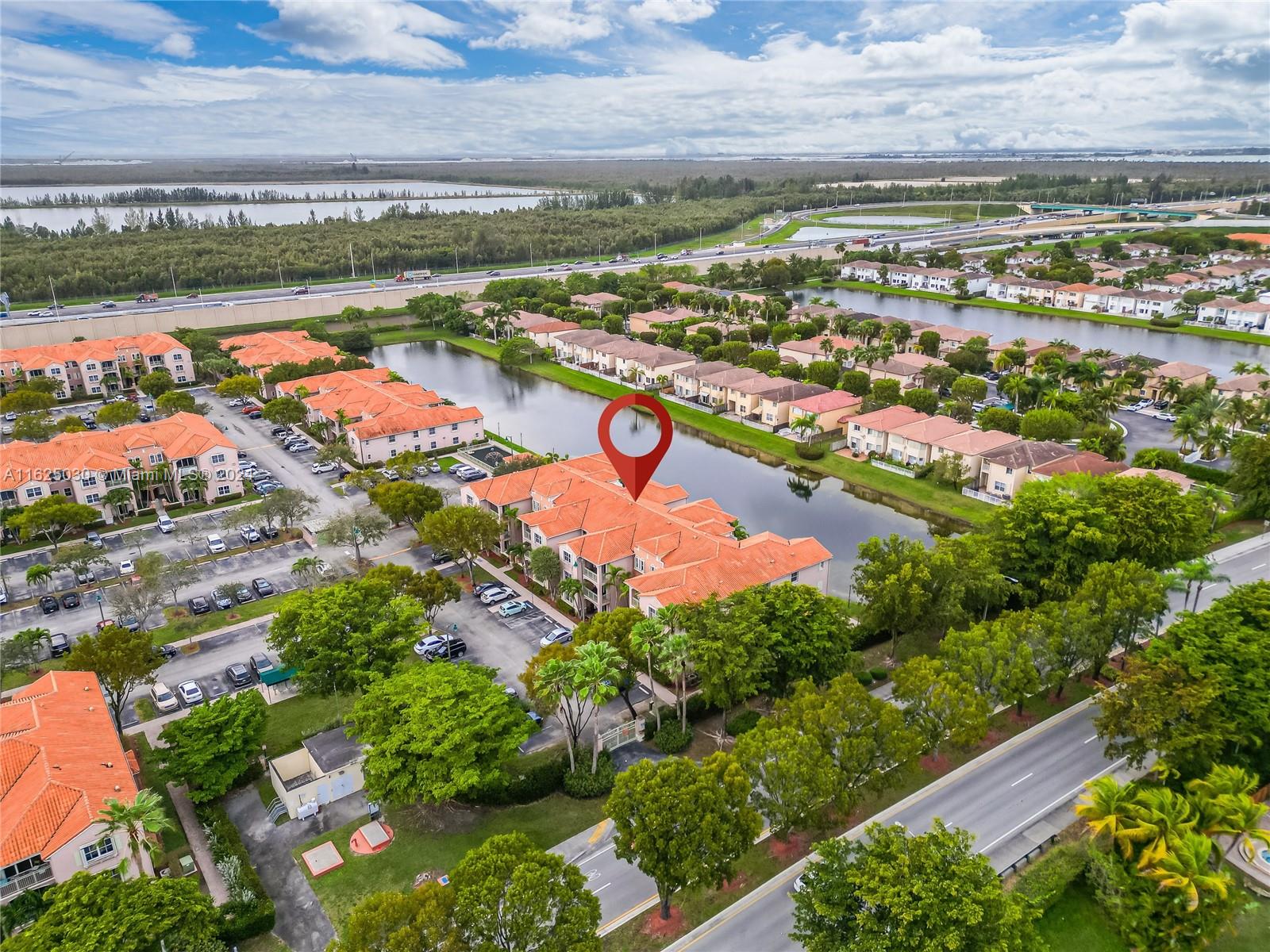 Aerial view of homes surrounding a pond, with a red pin marking a home near the water.