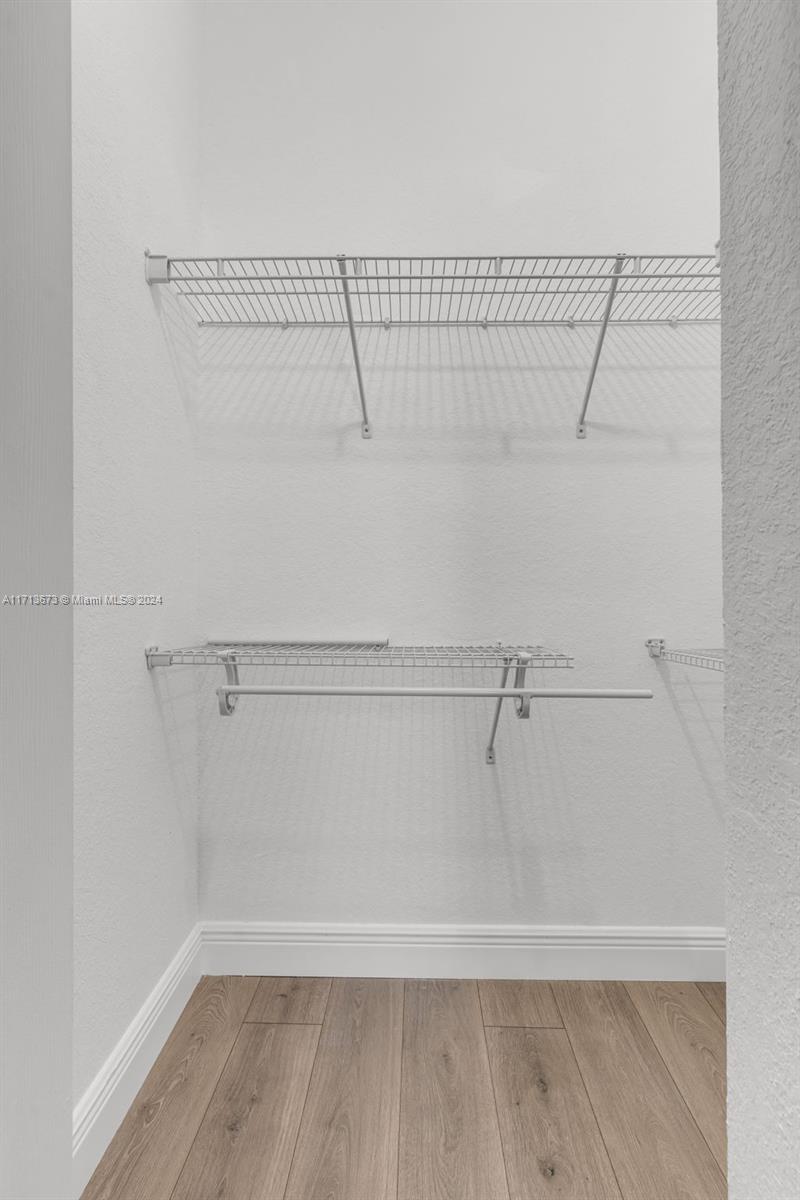 Walk-in closet with white wire shelving, a hanging rod, and light wood-look flooring.