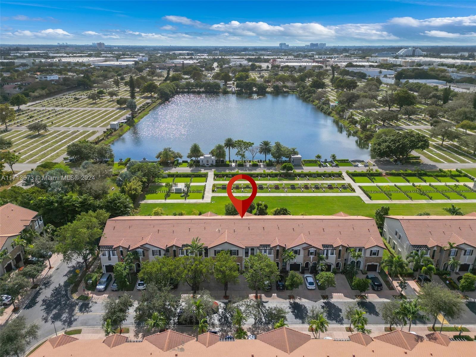 Aerial view of attached townhomes beside a lake, with a red pin marking one home.