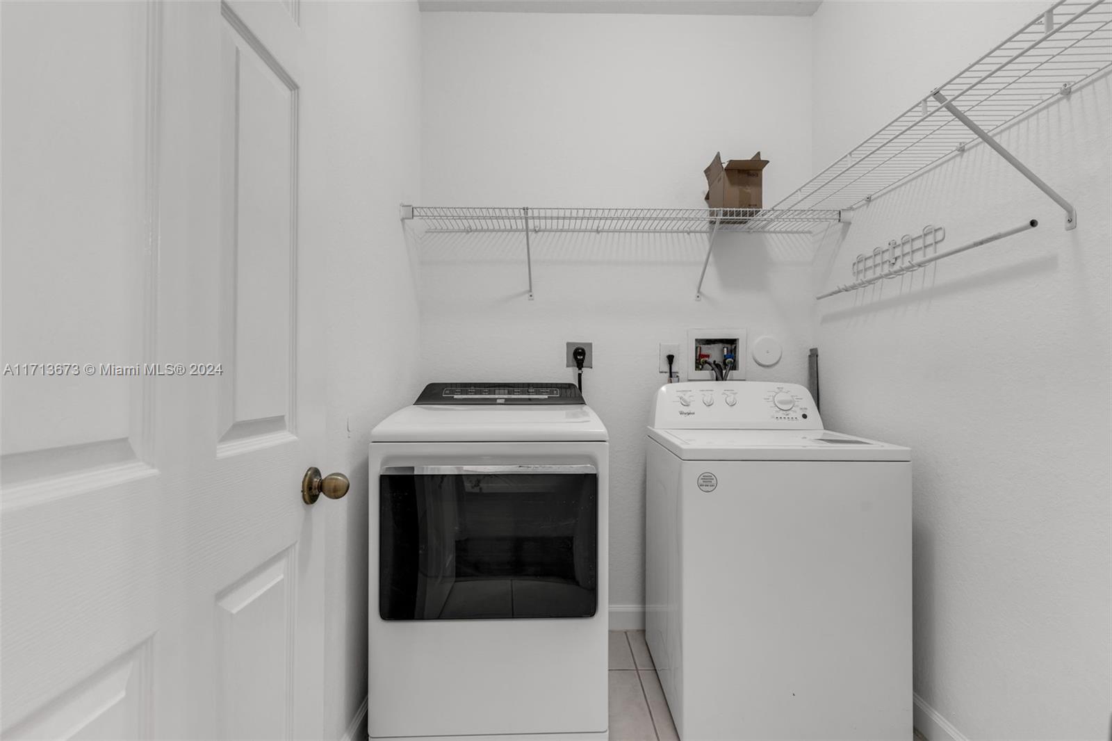 Laundry room with a front-loading dryer, top-loading washer, and wire storage shelves.