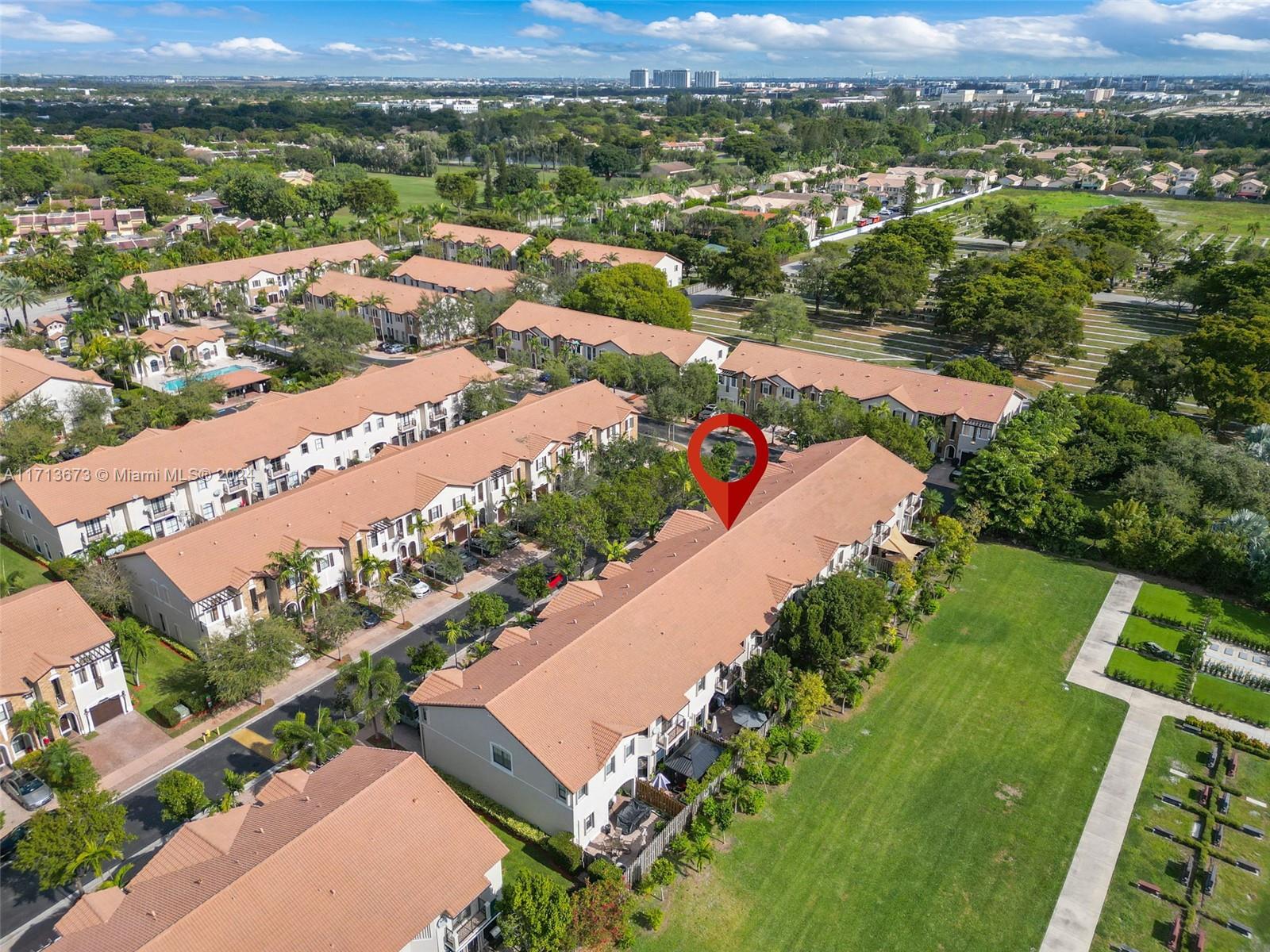 Aerial view of terracotta-roofed townhomes, with a red map pin marking the featured property.
