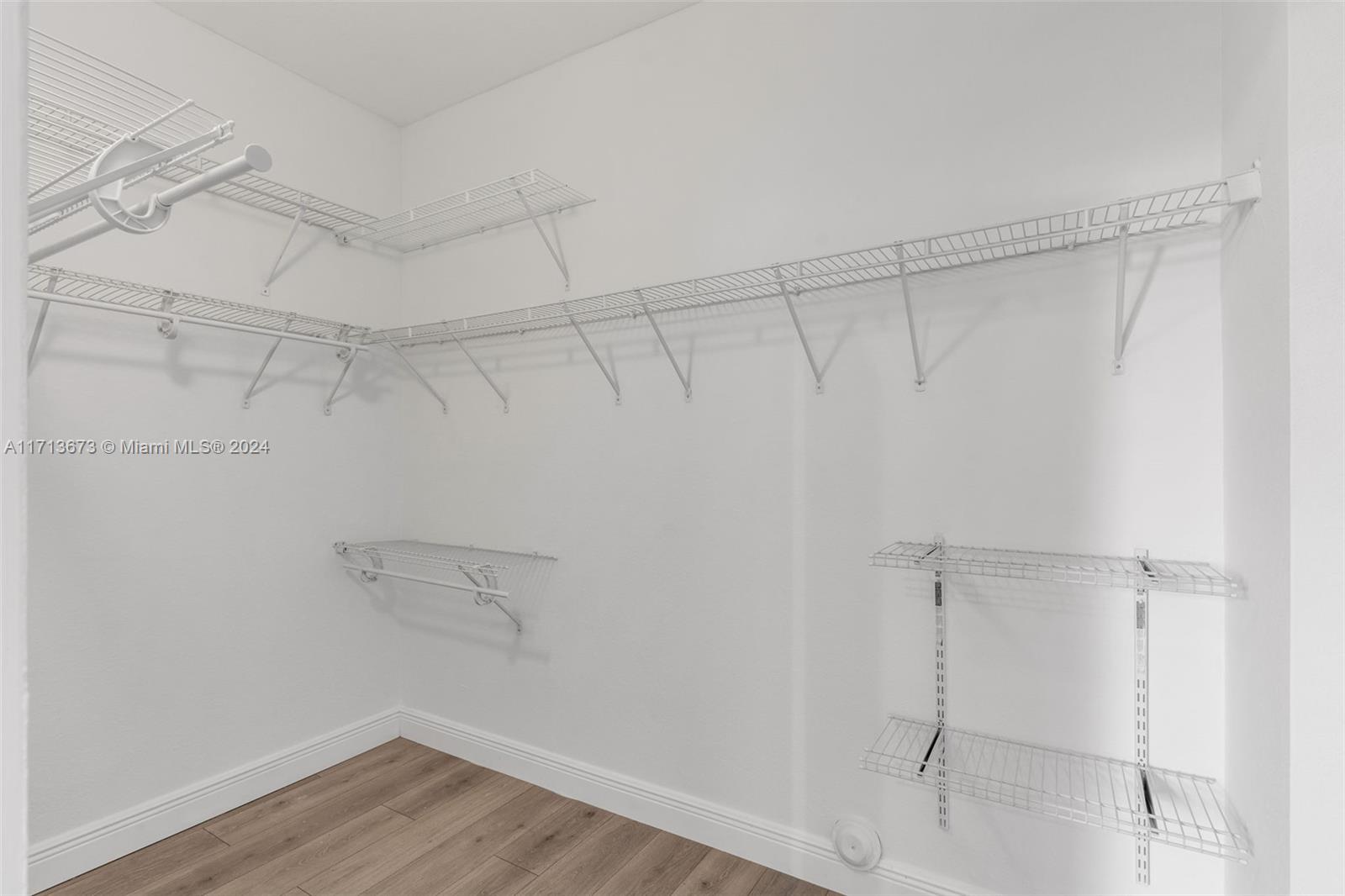 Walk-in closet with extensive white wire shelving and wood-look flooring.