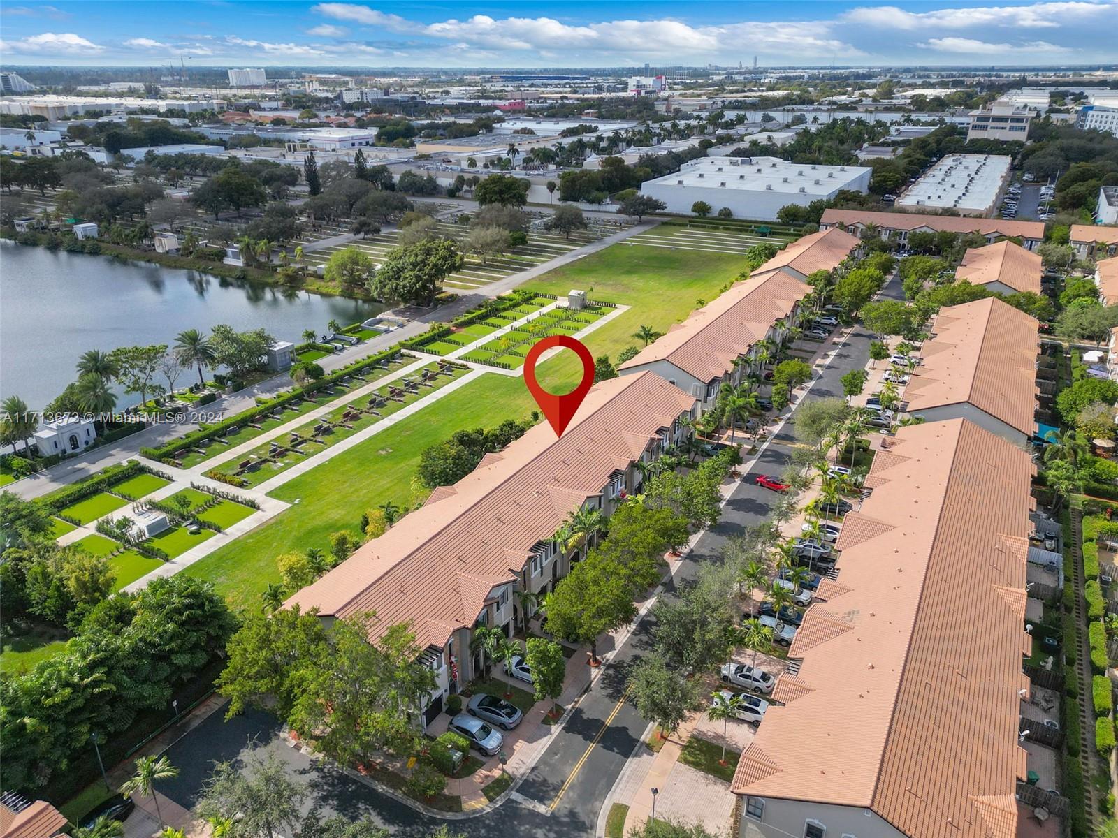 A red pin marks a townhouse in a terracotta-roofed community beside a lake.