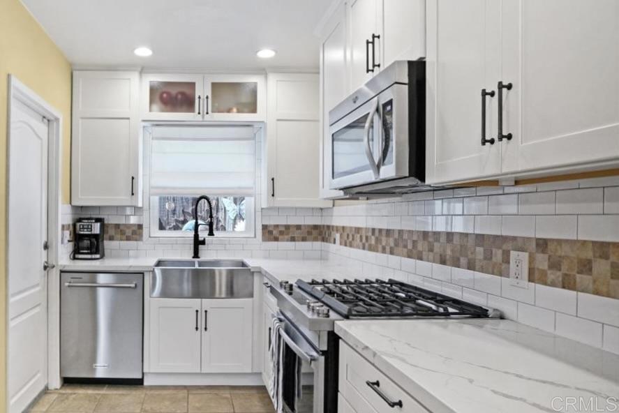 Kitchen with white shaker cabinets, stainless steel appliances, gas range, and white subway tile backsplash.
