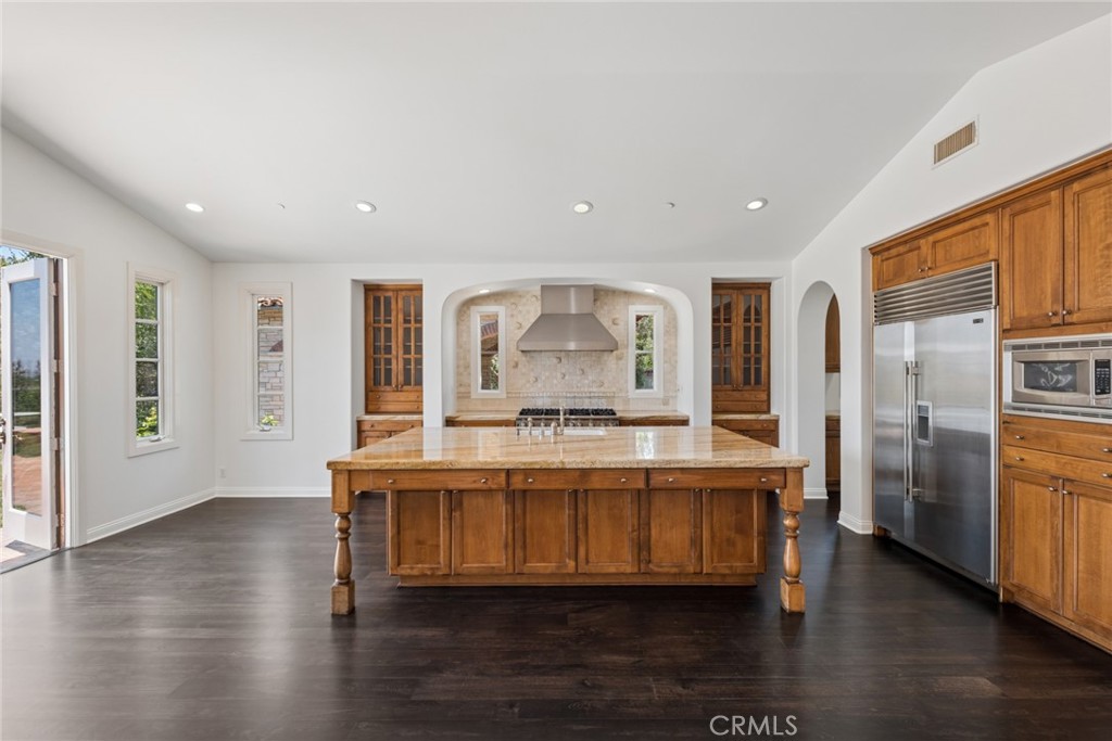 Spacious kitchen with a large wood island, stone countertop, and stainless steel appliances.