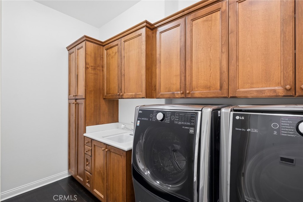Laundry room with front-loading washer and dryer beneath extensive wood cabinetry.