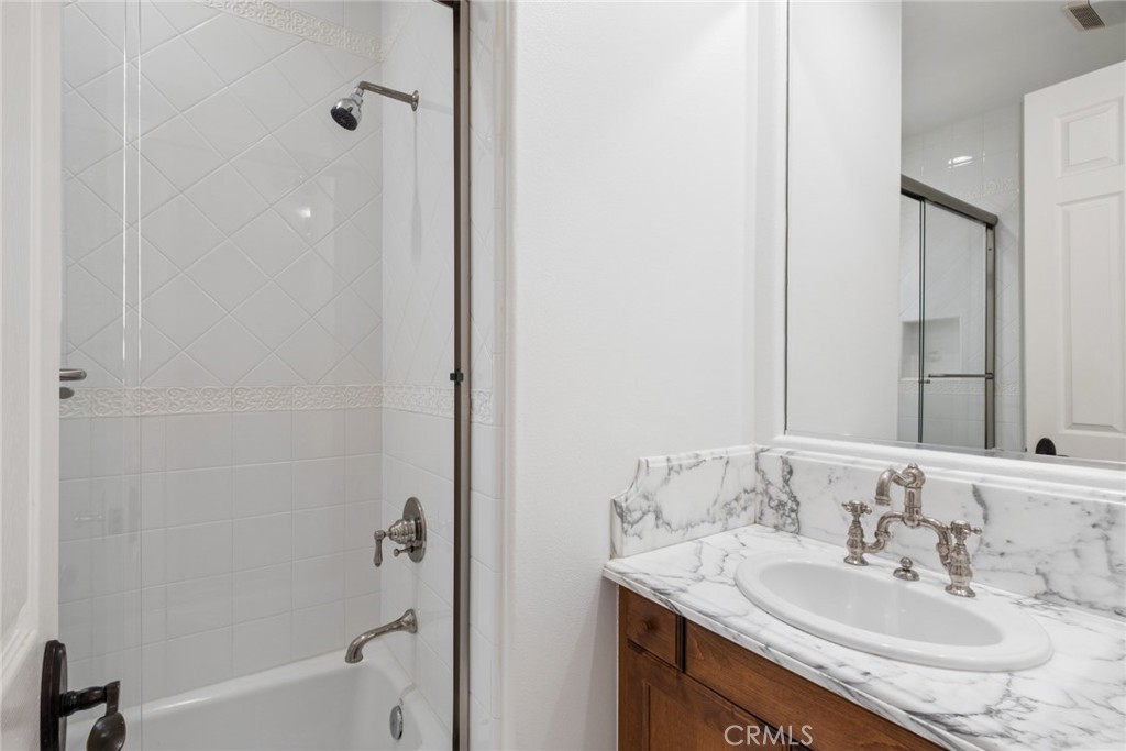Bathroom with a glass shower enclosure and marble-look vanity over a dark wood cabinet.
