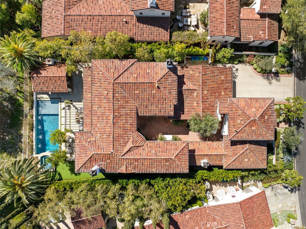 Aerial view of a terracotta-tiled home with a courtyard, swimming pool, and landscaped grounds.