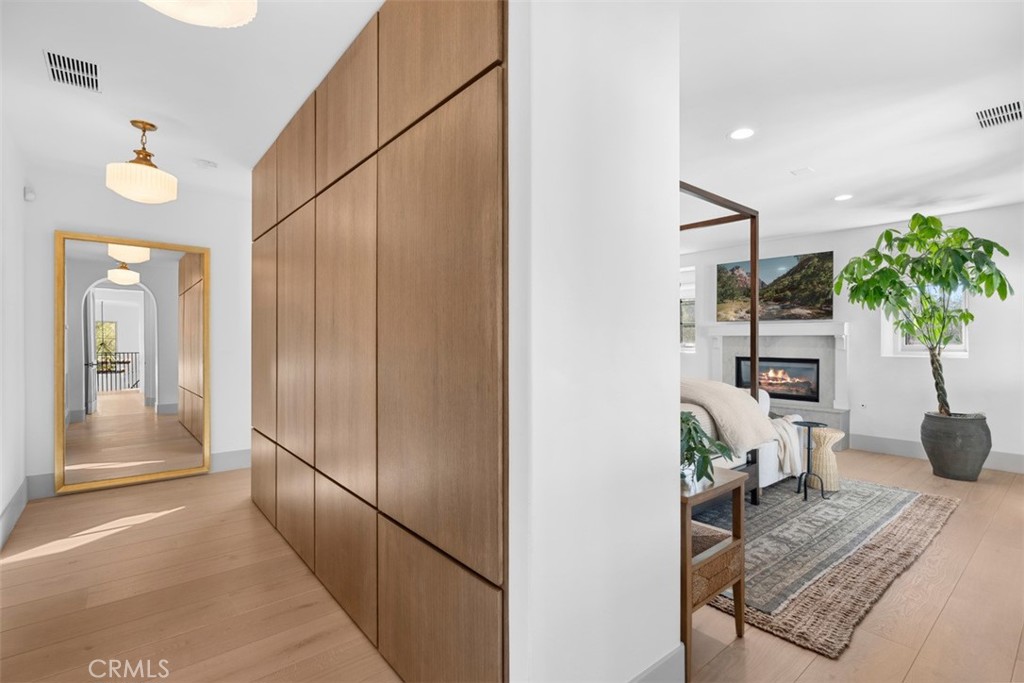 Entry hall with floor-to-ceiling wood cabinetry opening onto a living room with a fireplace.