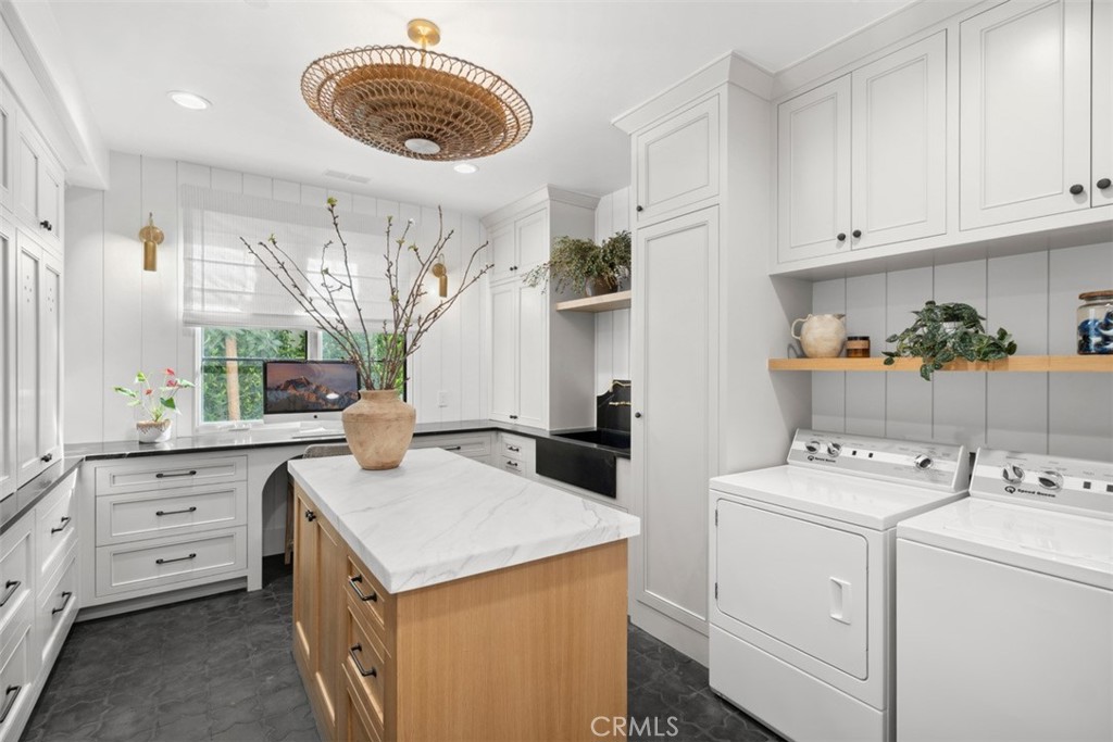 Bright kitchen with white cabinetry, marble island, and washer and dryer.