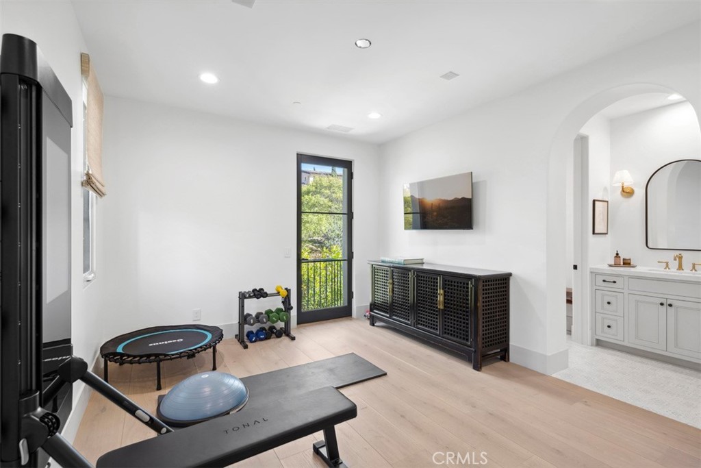 Home gym with a Tonal machine, free weights, rebounder, and arched opening to a bathroom.