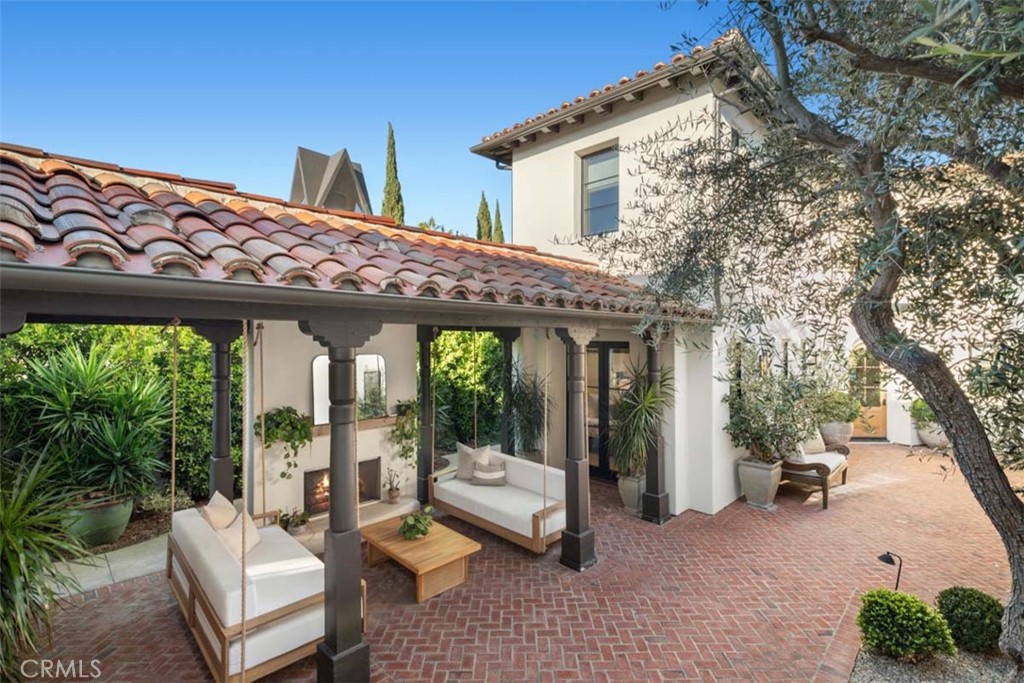 Mediterranean-style home courtyard with brick paving, covered seating, and potted plants.