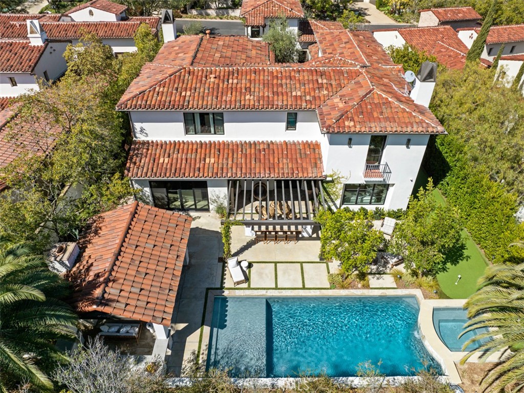Aerial view of a white stucco home with terracotta roofs and a backyard pool.