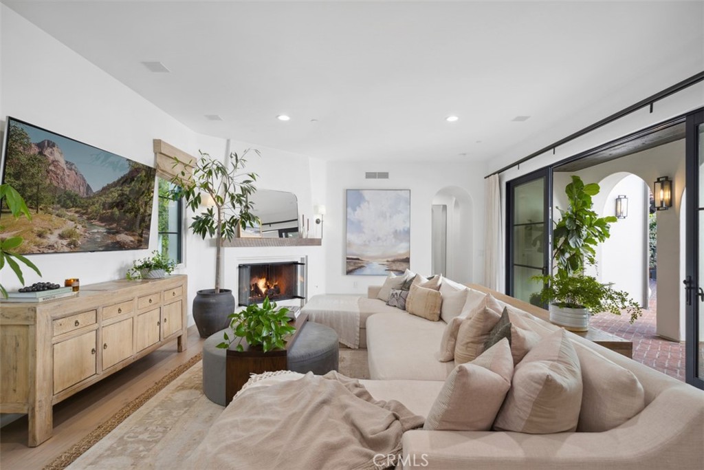 Living room with a cream sectional, wood-burning fireplace, and sliding glass doors opening to a brick patio.