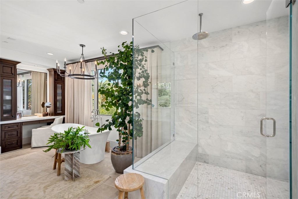 Luxury bathroom with a marble walk-in shower, freestanding tub, and dark wood vanity.