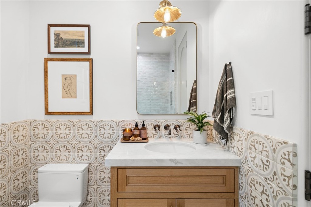 Bathroom vanity with patterned tile, a wood cabinet, and a framed mirror.