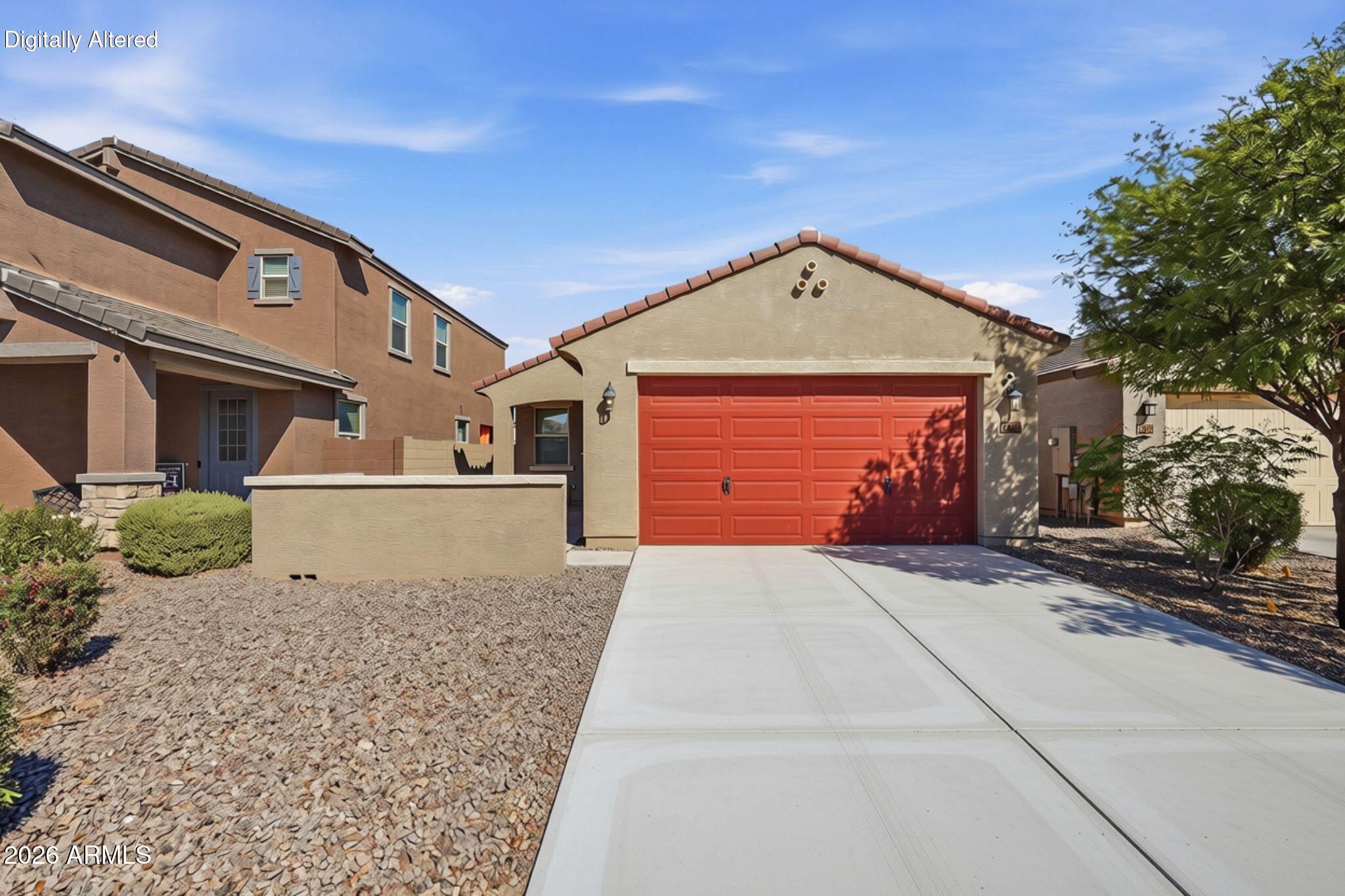 Stucco home with a red double garage door, wide driveway, and desert landscaping.