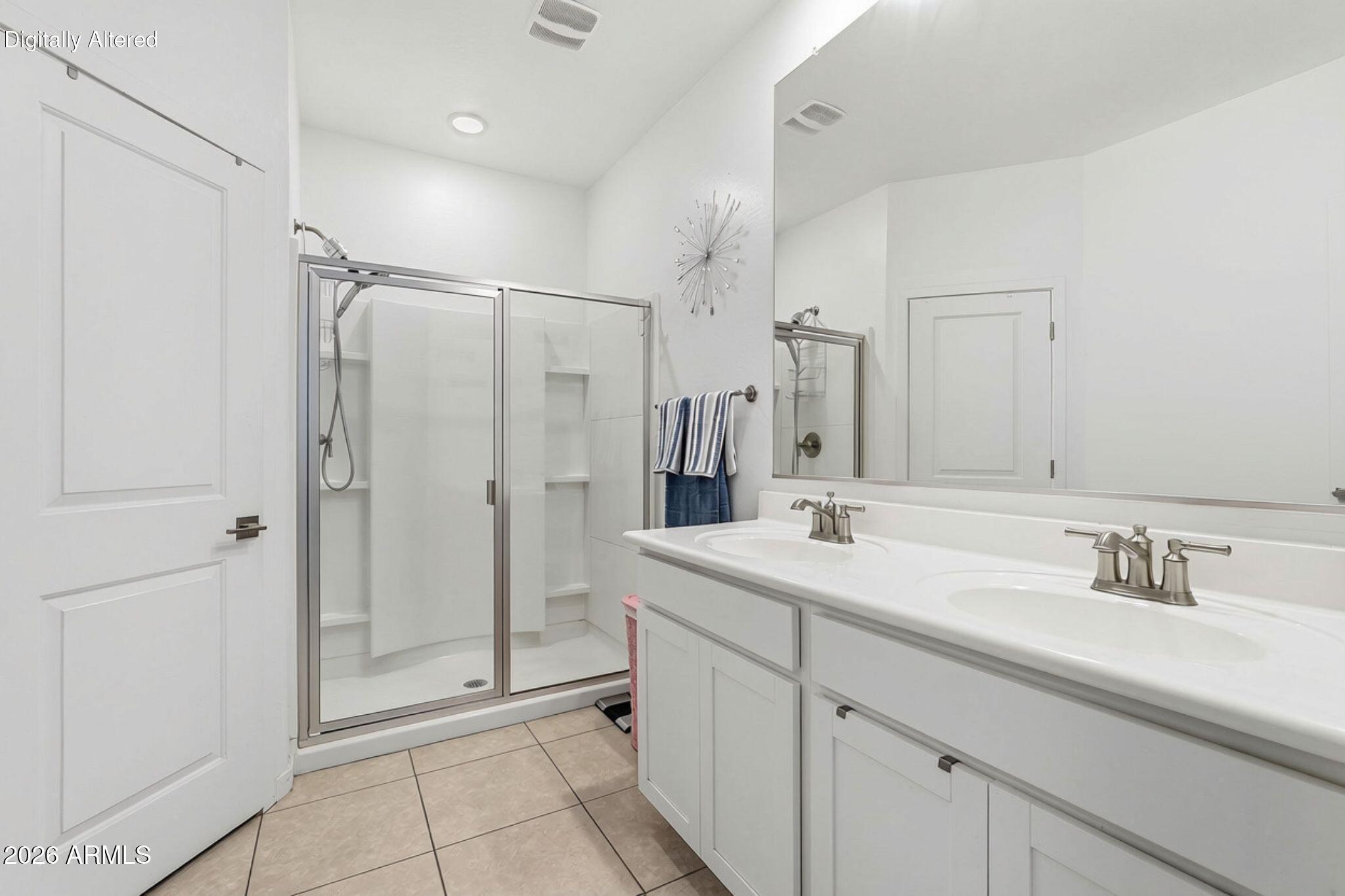 Bright bathroom with a glass-enclosed shower and long double-sink vanity.