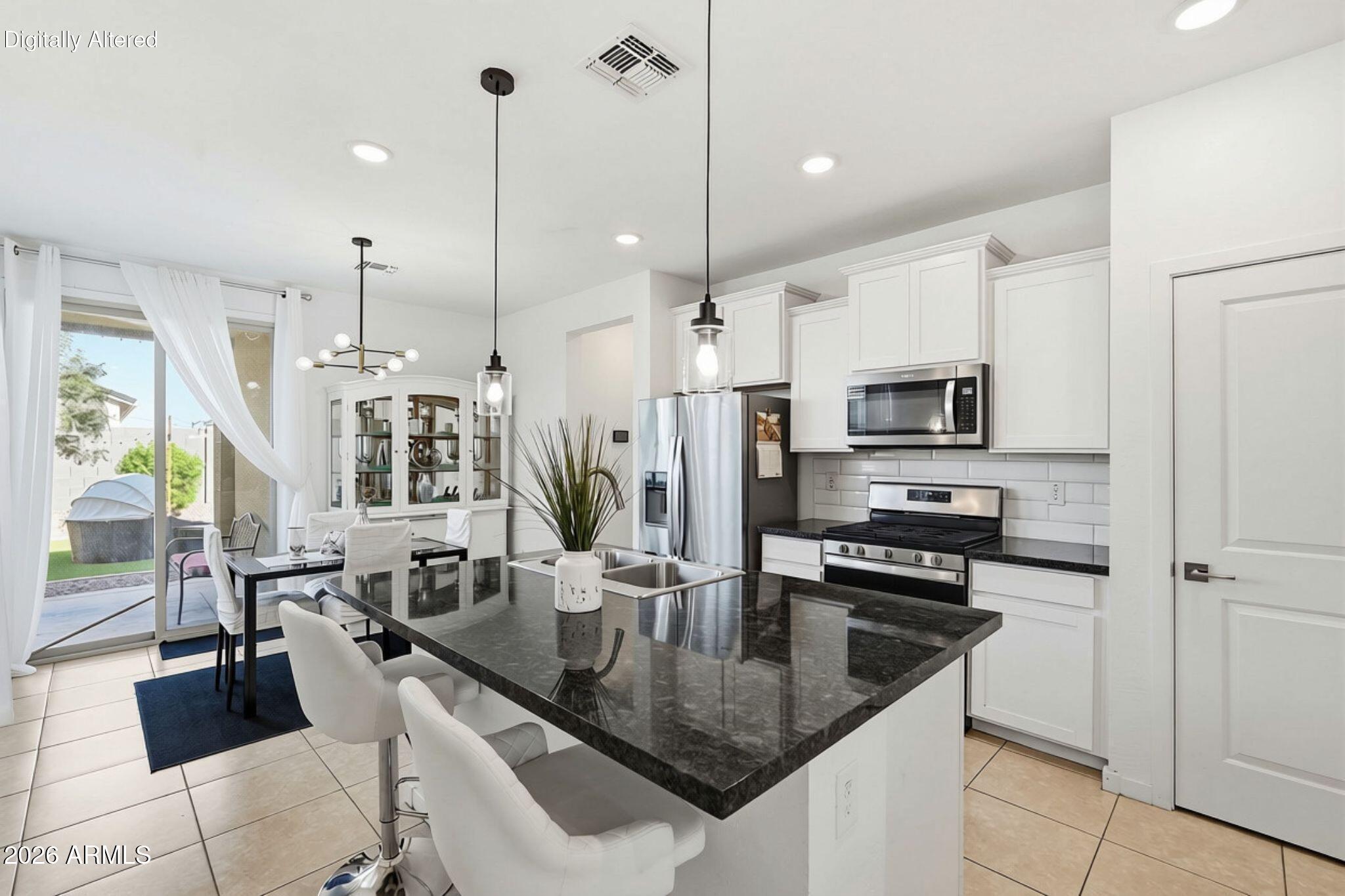 Kitchen and dining area with a dark stone island, white cabinets, stainless steel appliances, and sliding glass doors.