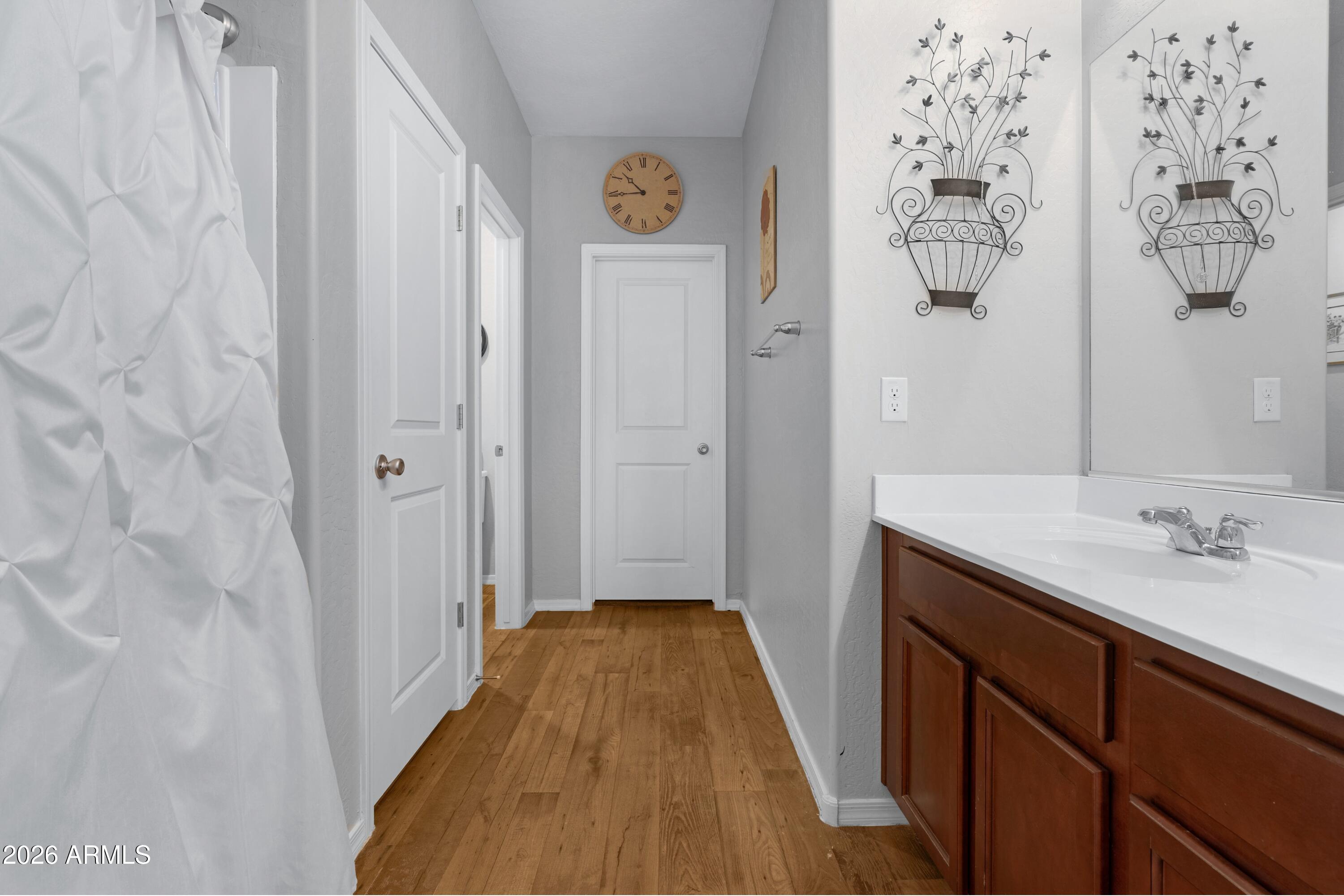 Bathroom with a wood-finish vanity, white countertop, and wood-plank flooring.
