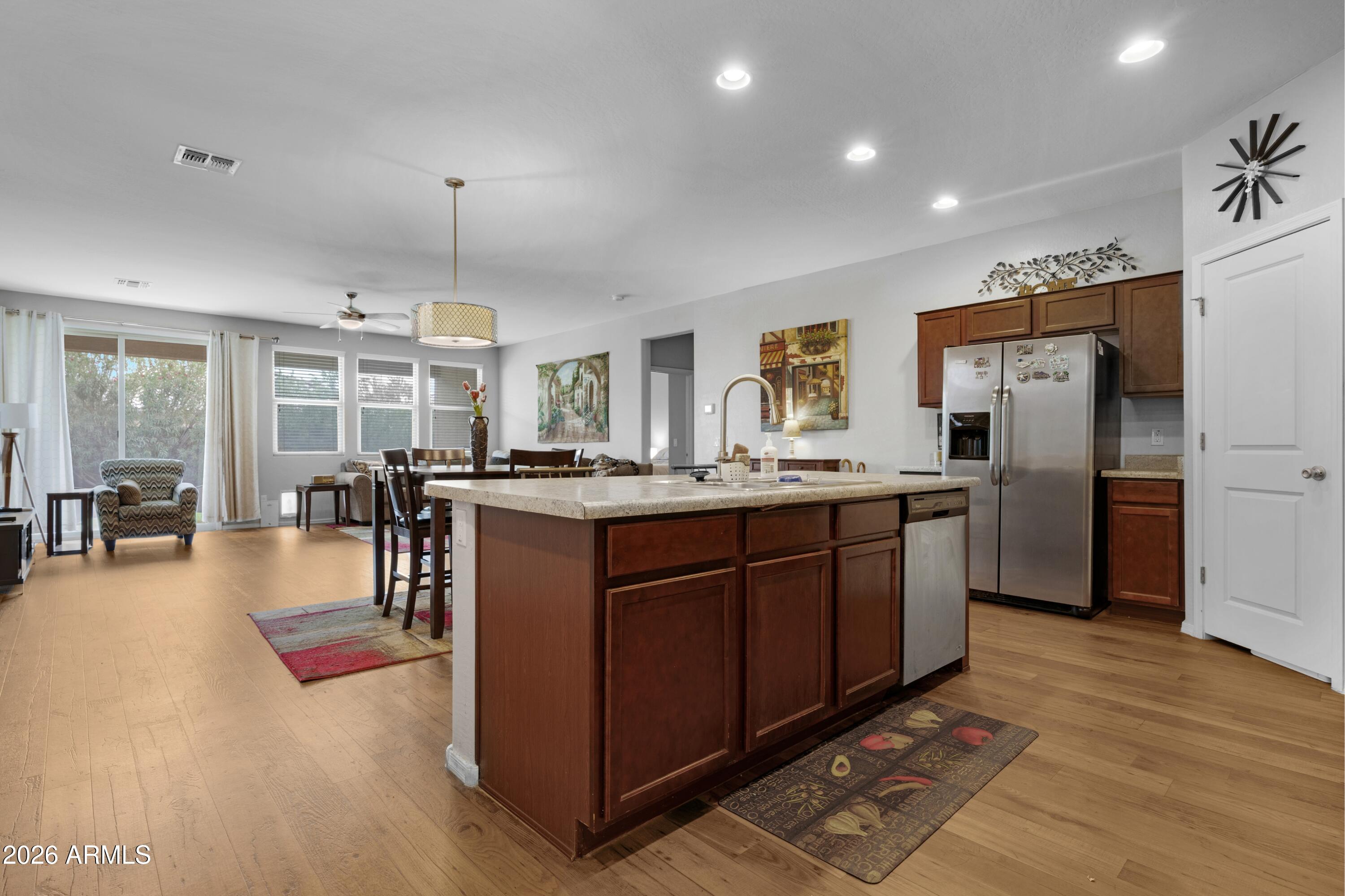 Kitchen with a large dark wood island and stone countertop opening to a bright dining and living area.