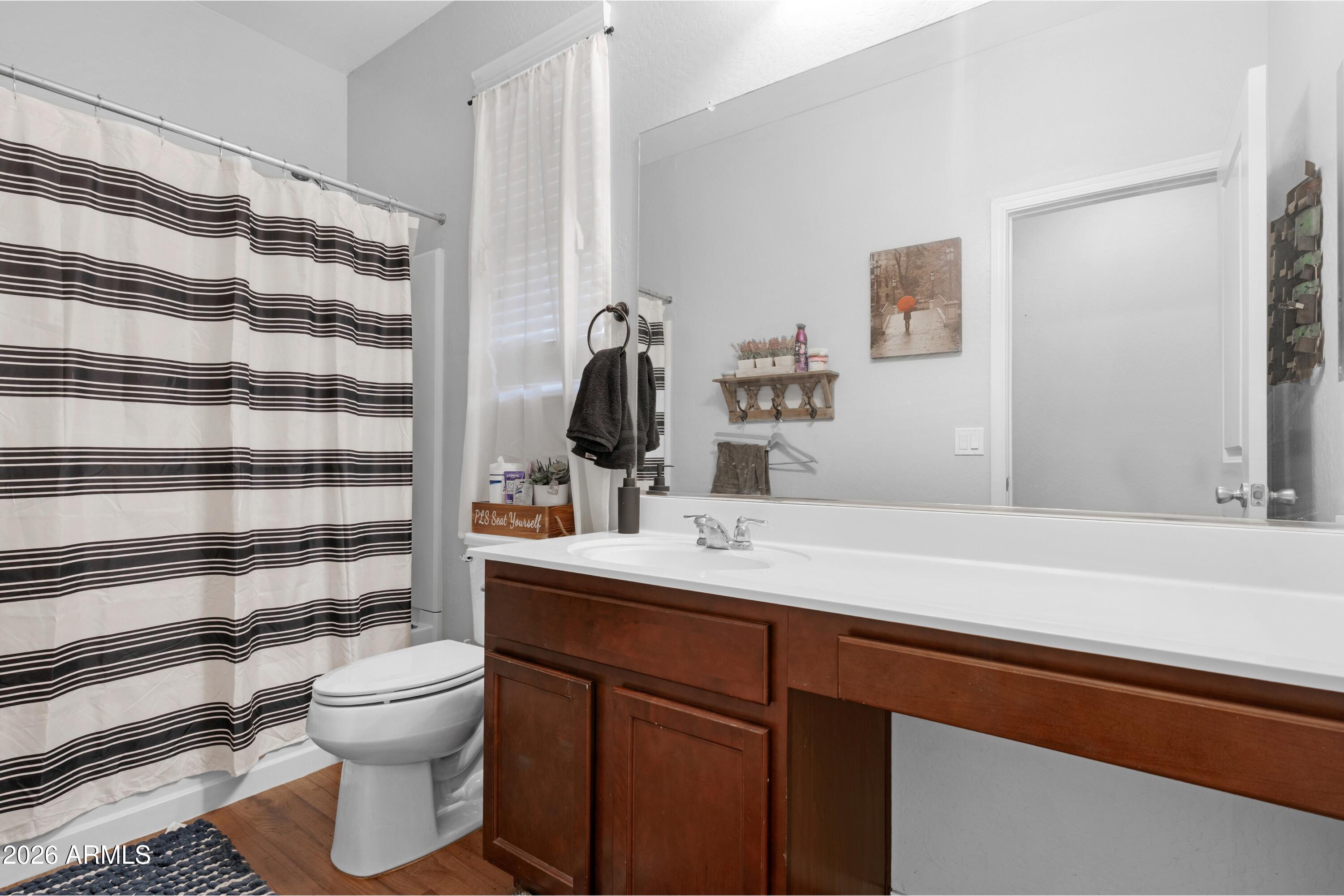 Bathroom with a dark wood vanity, large mirror, and striped shower curtain.