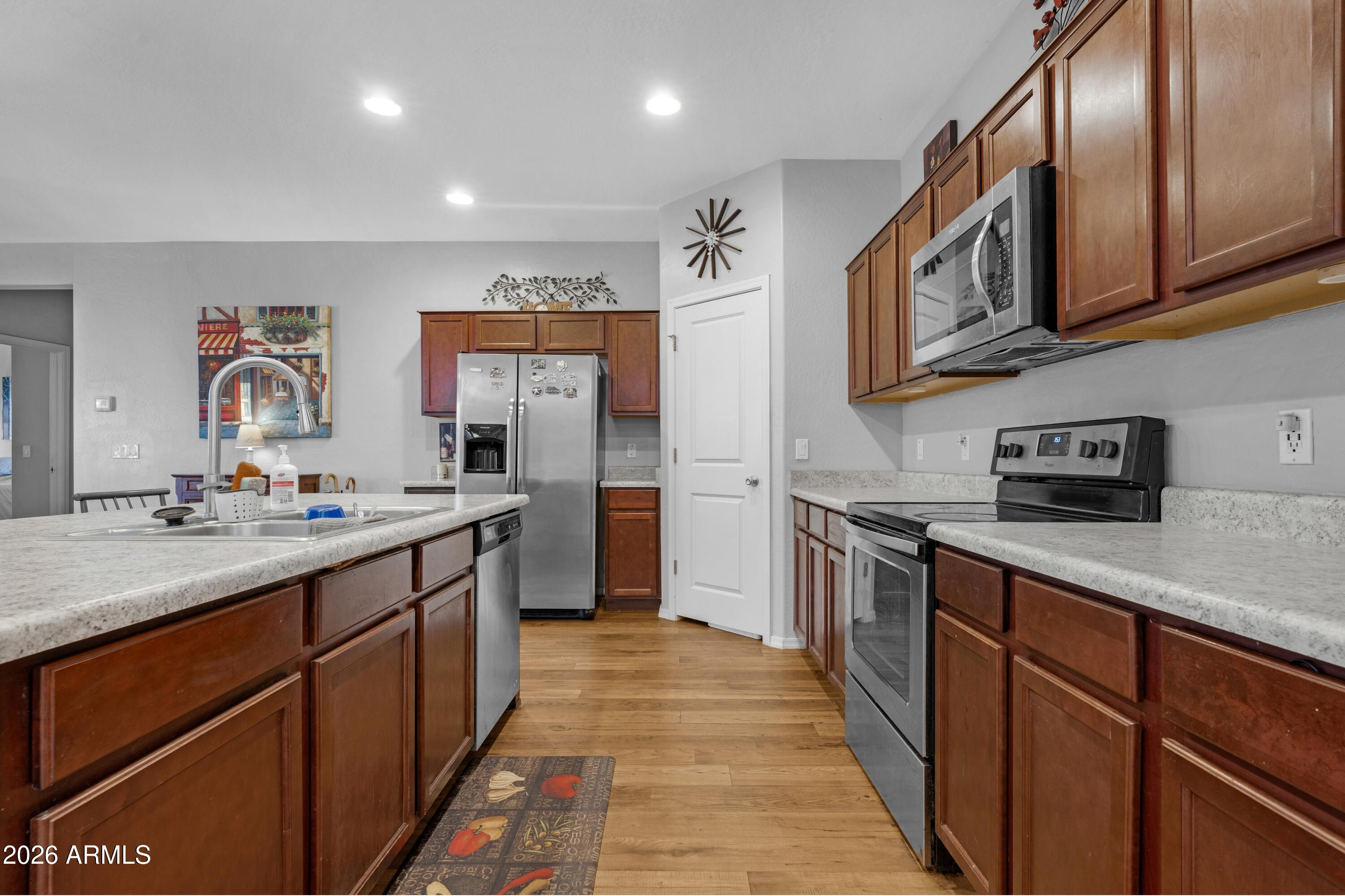 Kitchen with dark wood cabinets, stone countertops, and stainless steel appliances.