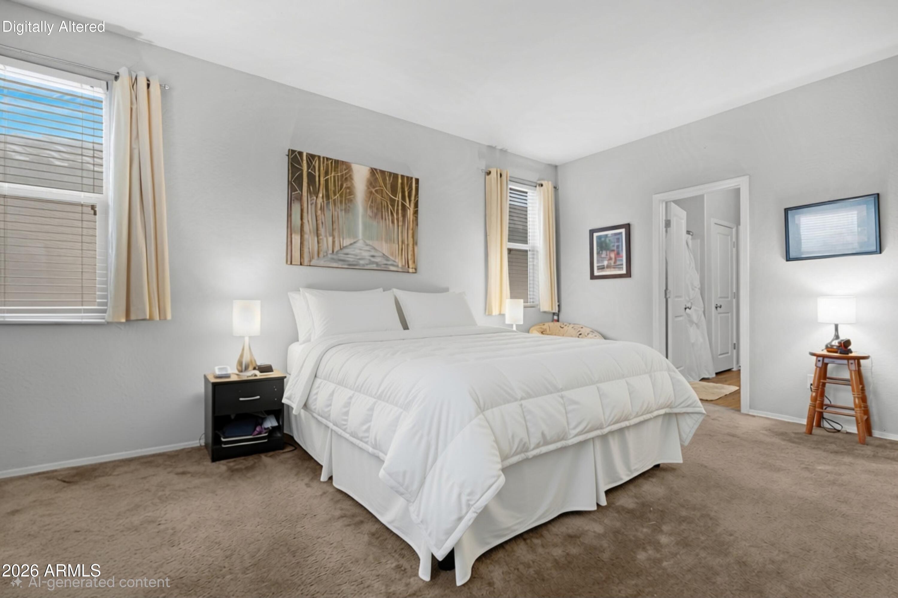 Bedroom with a large white bed, beige carpet, and framed woodland artwork above the headboard.