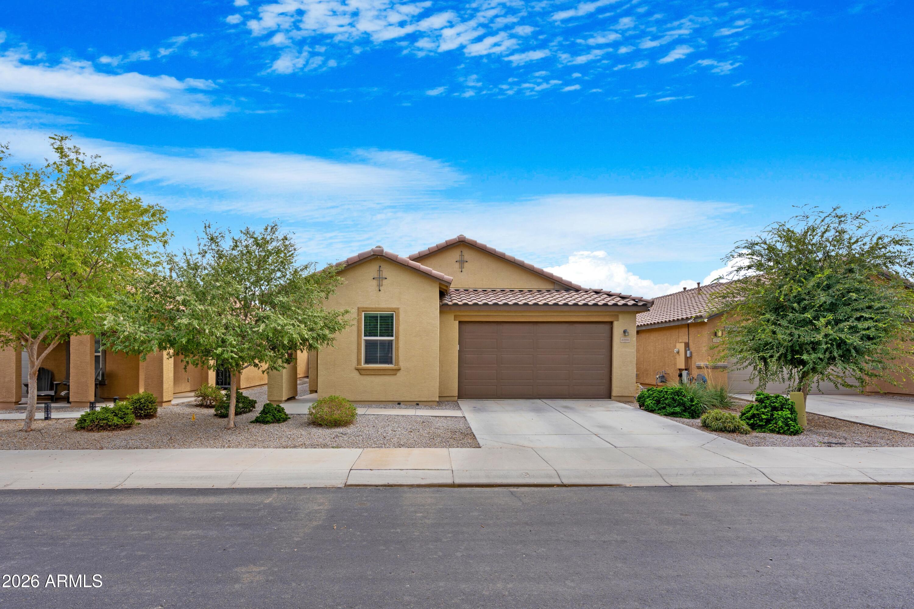 Tan stucco home with a tile roof, two-car garage, and desert landscaping.
