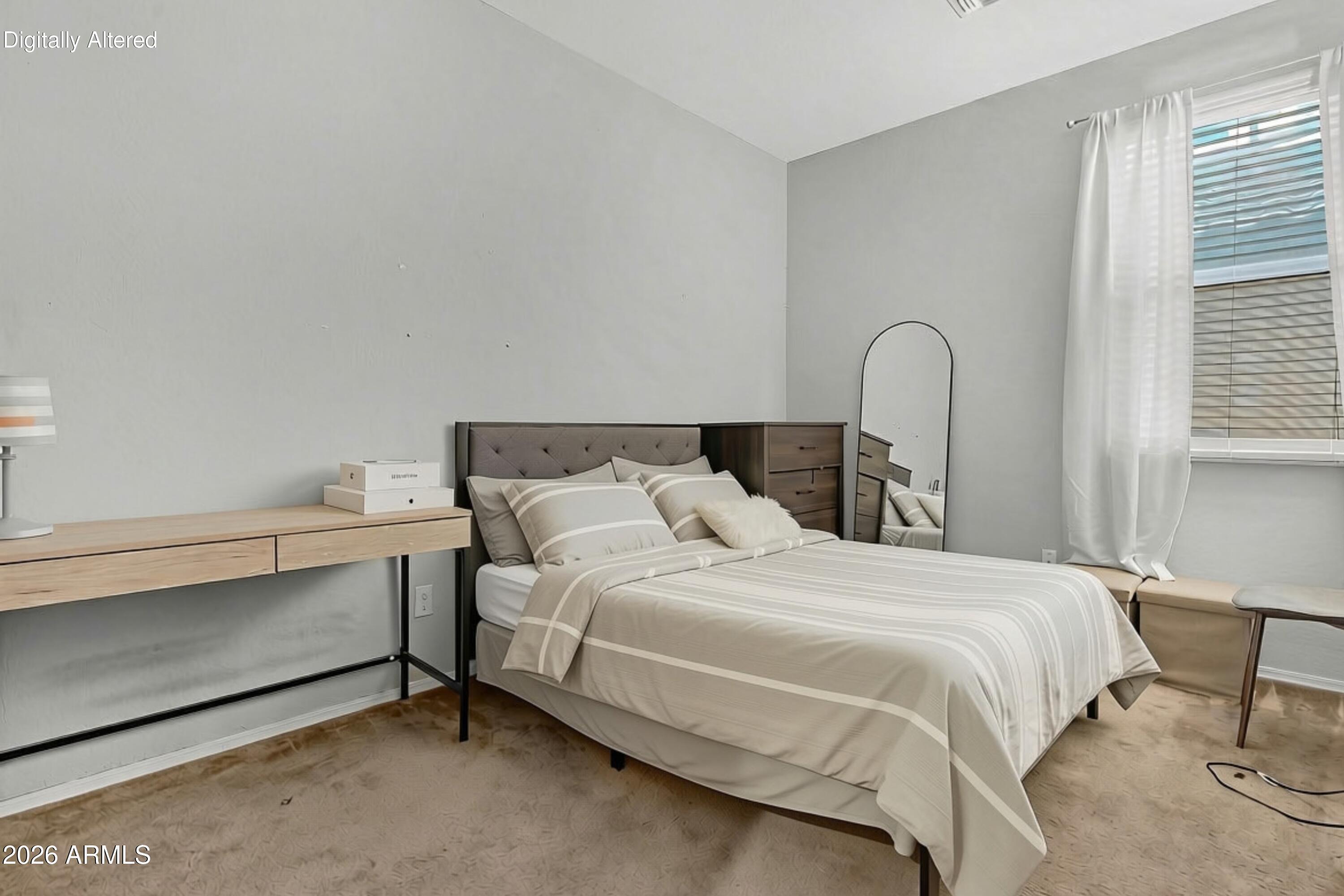 Bedroom with cream striped bedding, a light wood desk, and a tall arched mirror.