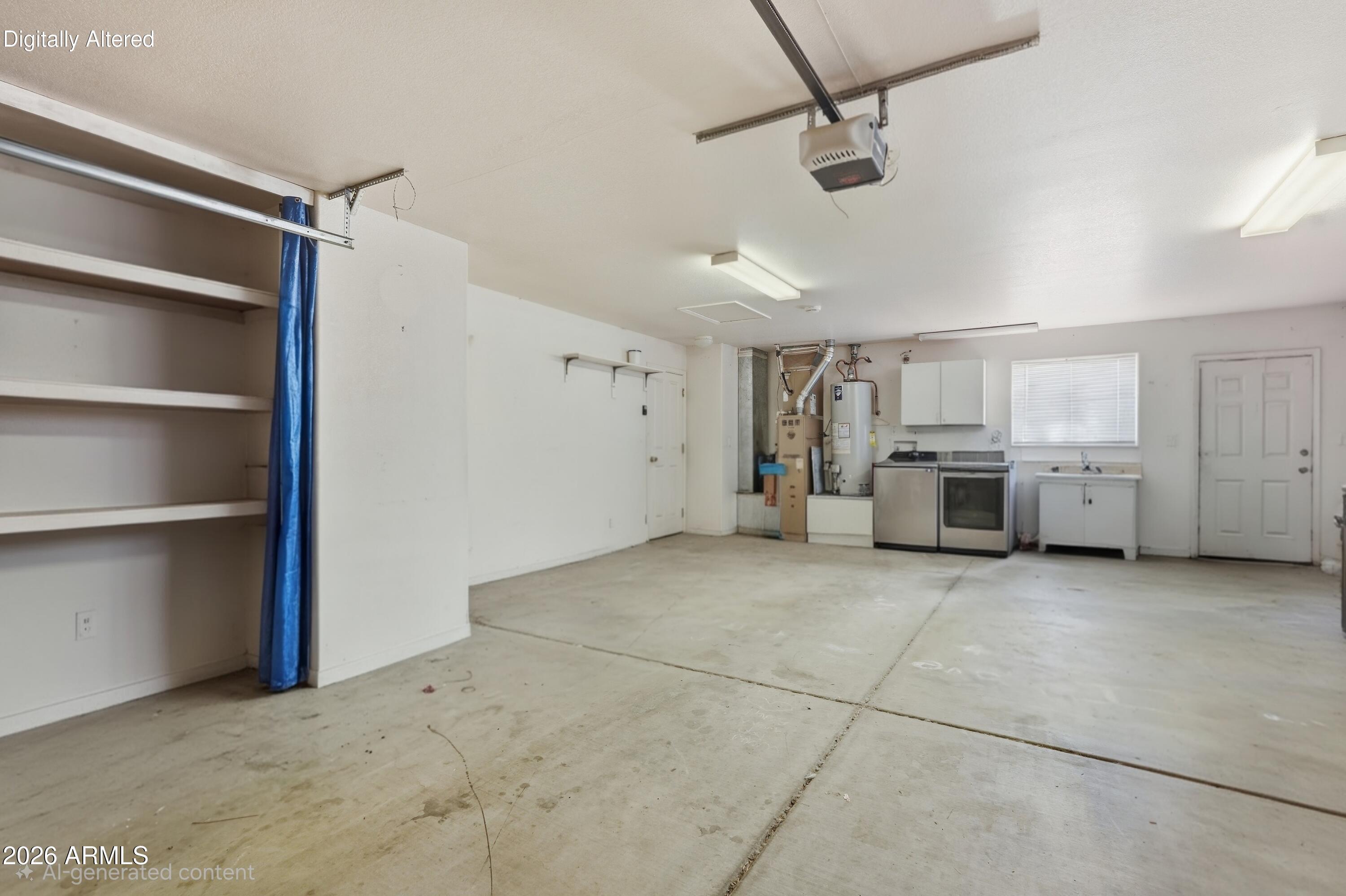 Empty garage with concrete flooring, wall shelving, utility appliances, cabinets, and a sink.