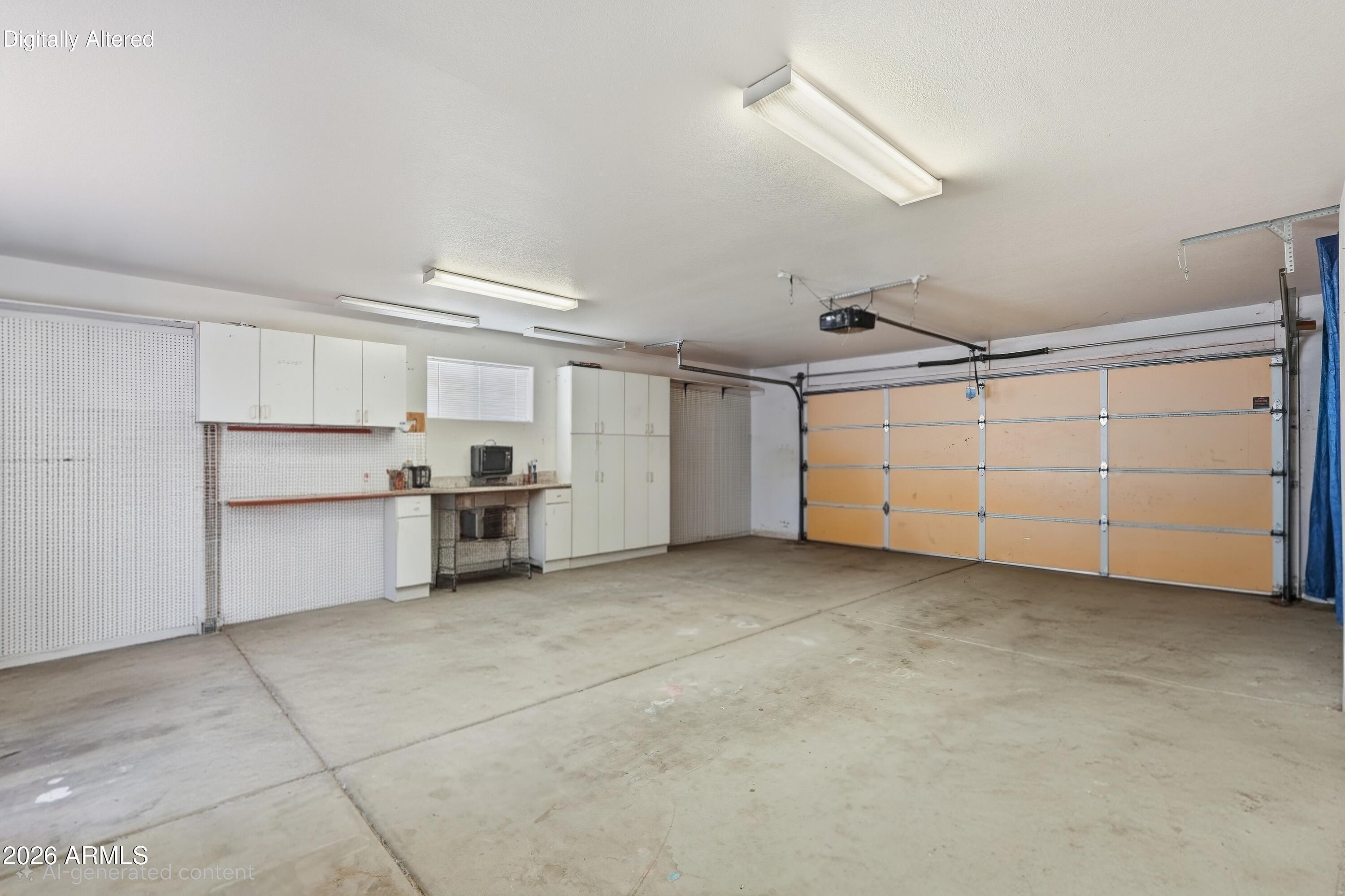 Empty garage with built-in cabinets and workbench beside a large sectional garage door.