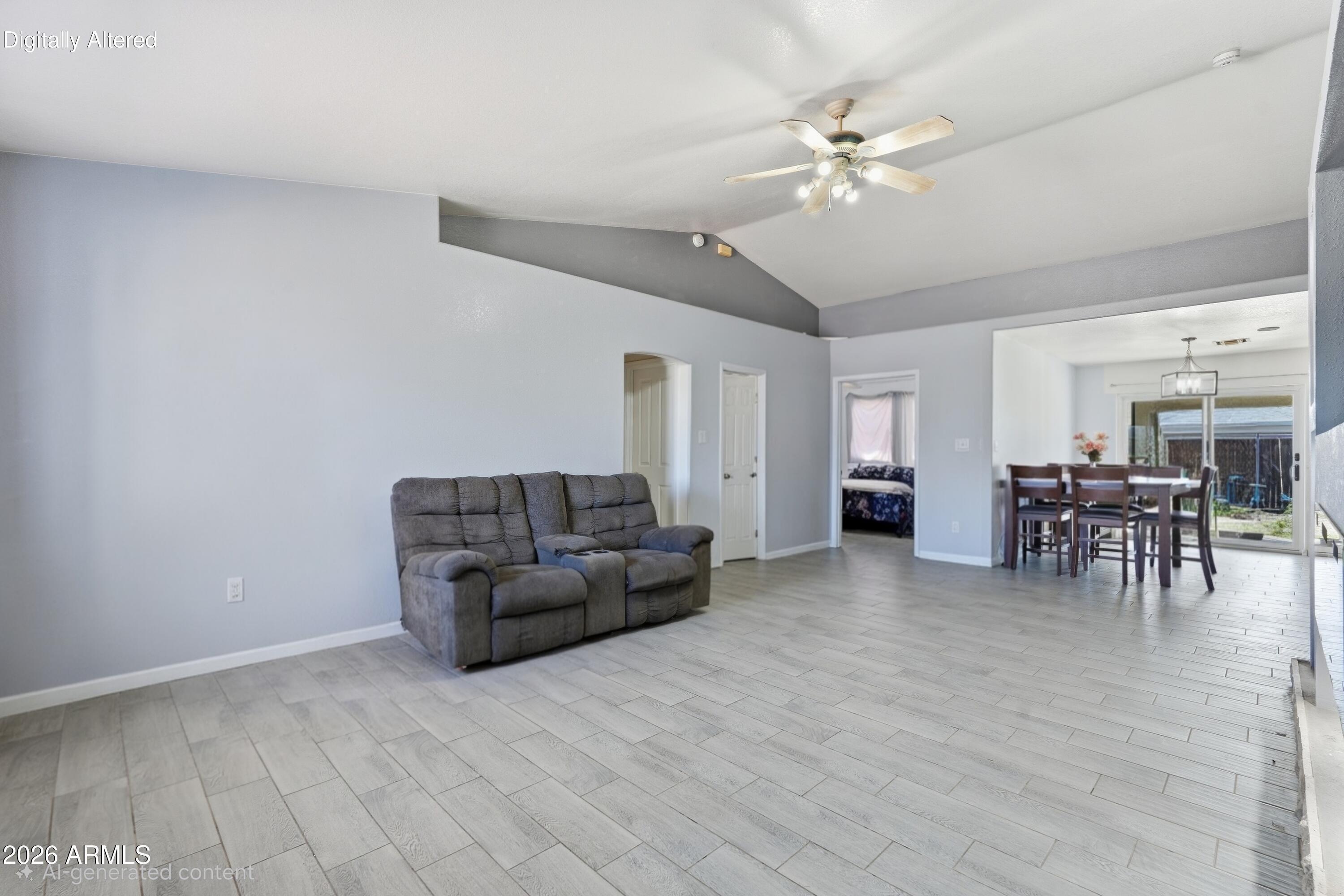 Furnished living room with reclining sofa, tiled floors, and an adjoining dining area beside sliding glass doors.