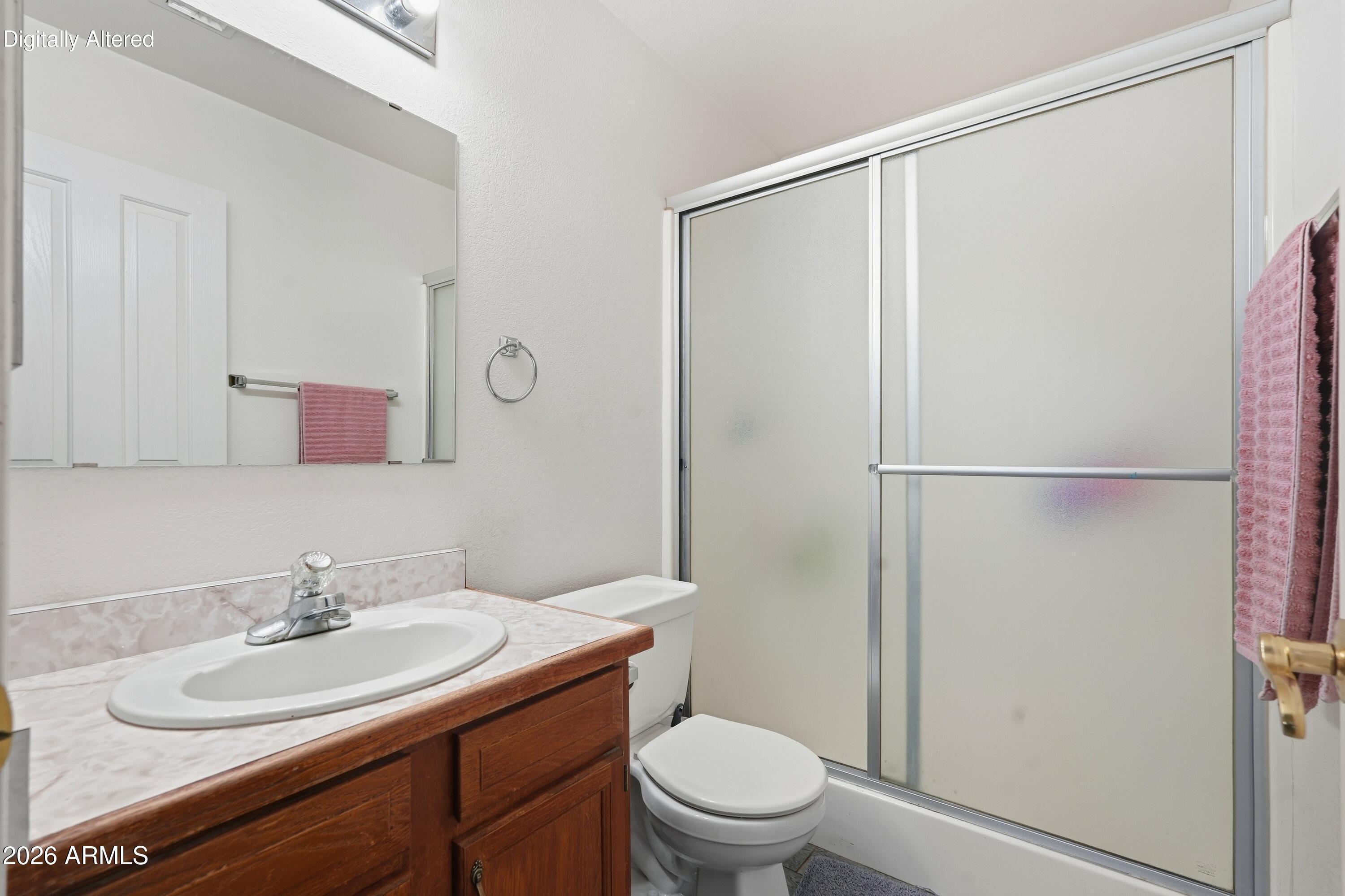 Bathroom with a wood vanity, white sink, toilet, and frosted-glass sliding shower doors.