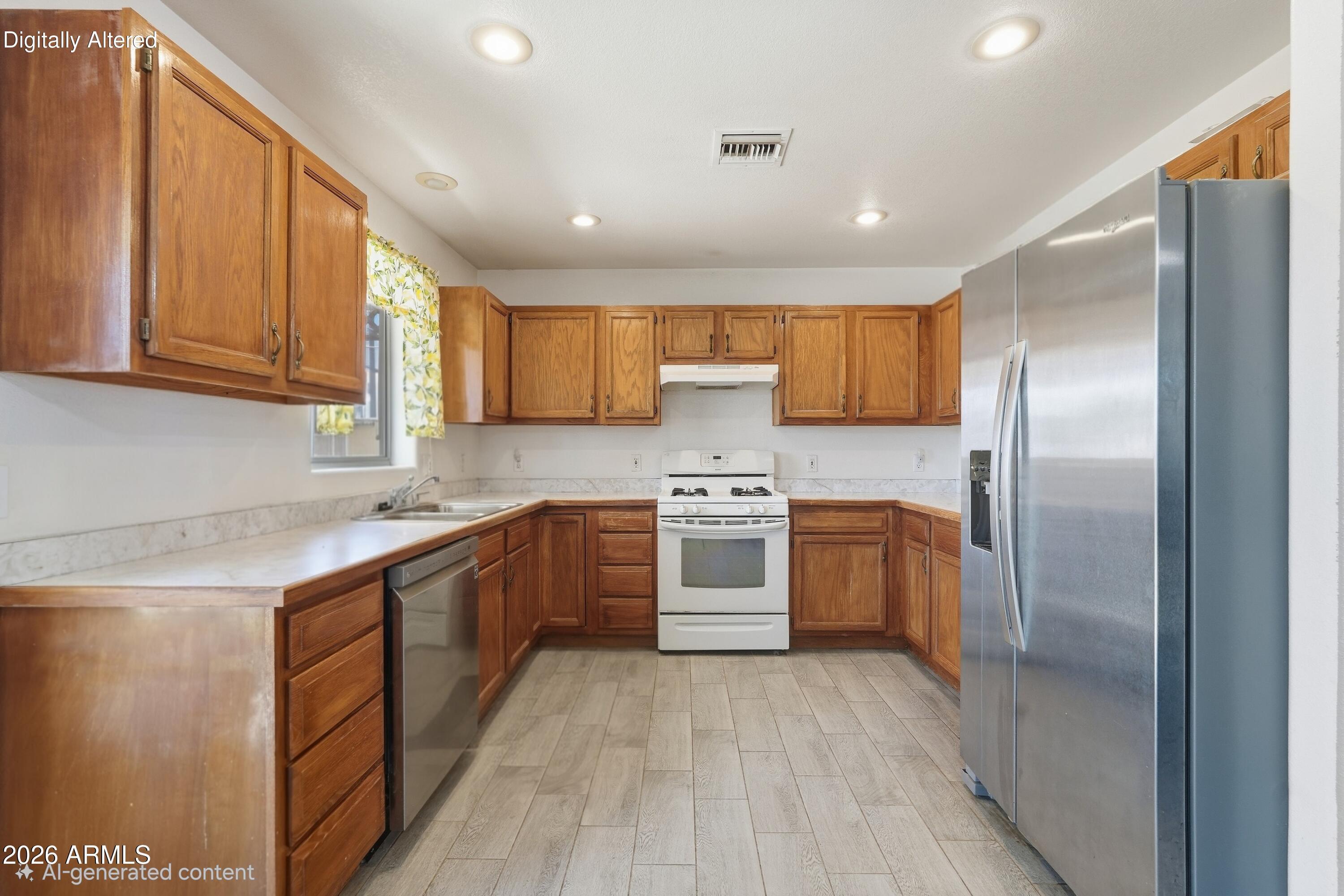 Kitchen with wood cabinets, stainless-steel refrigerator and dishwasher, and gray tile flooring.