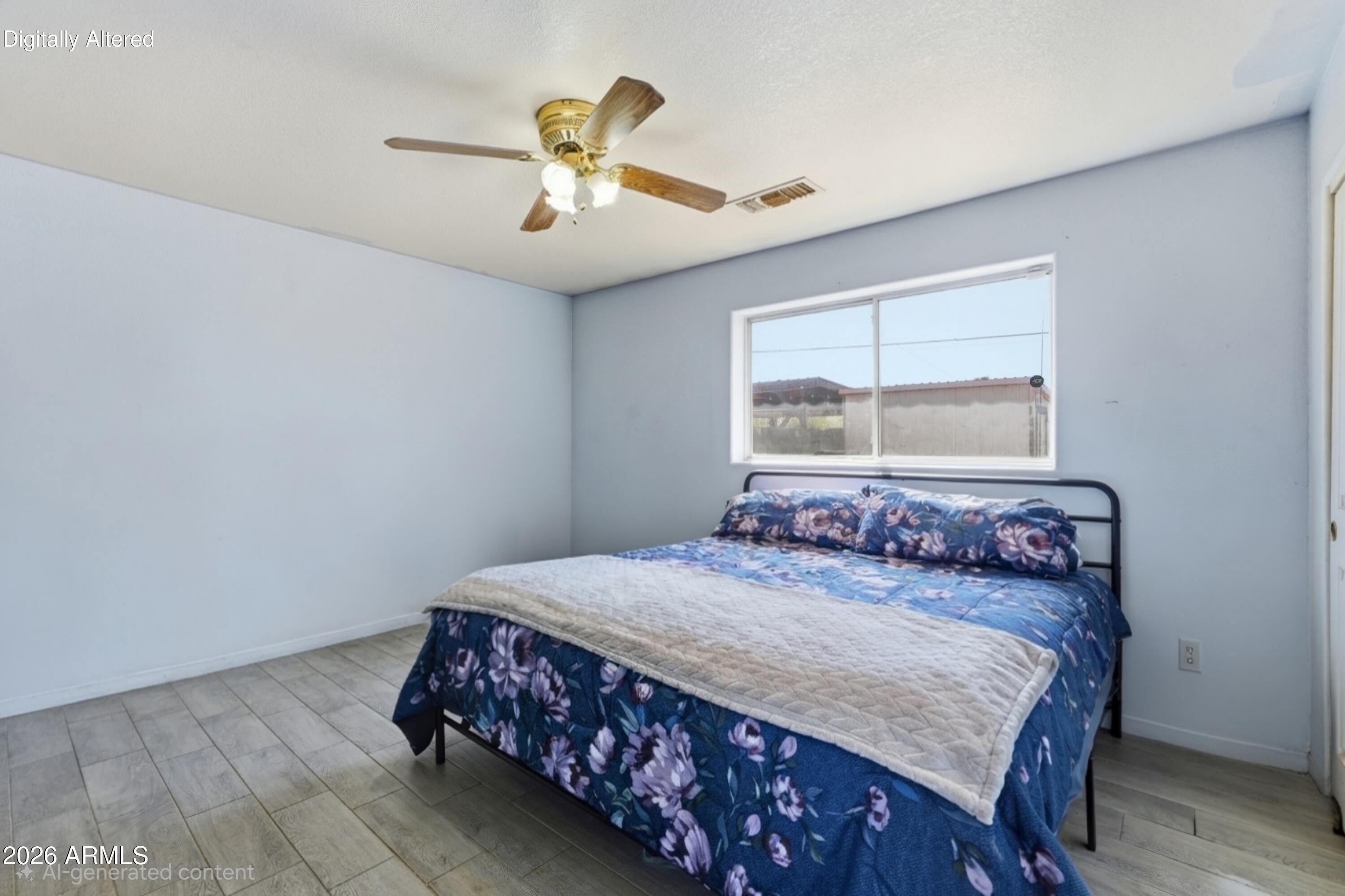 Bedroom with blue floral bedding, pale blue walls, gray tile floor, and a ceiling fan.