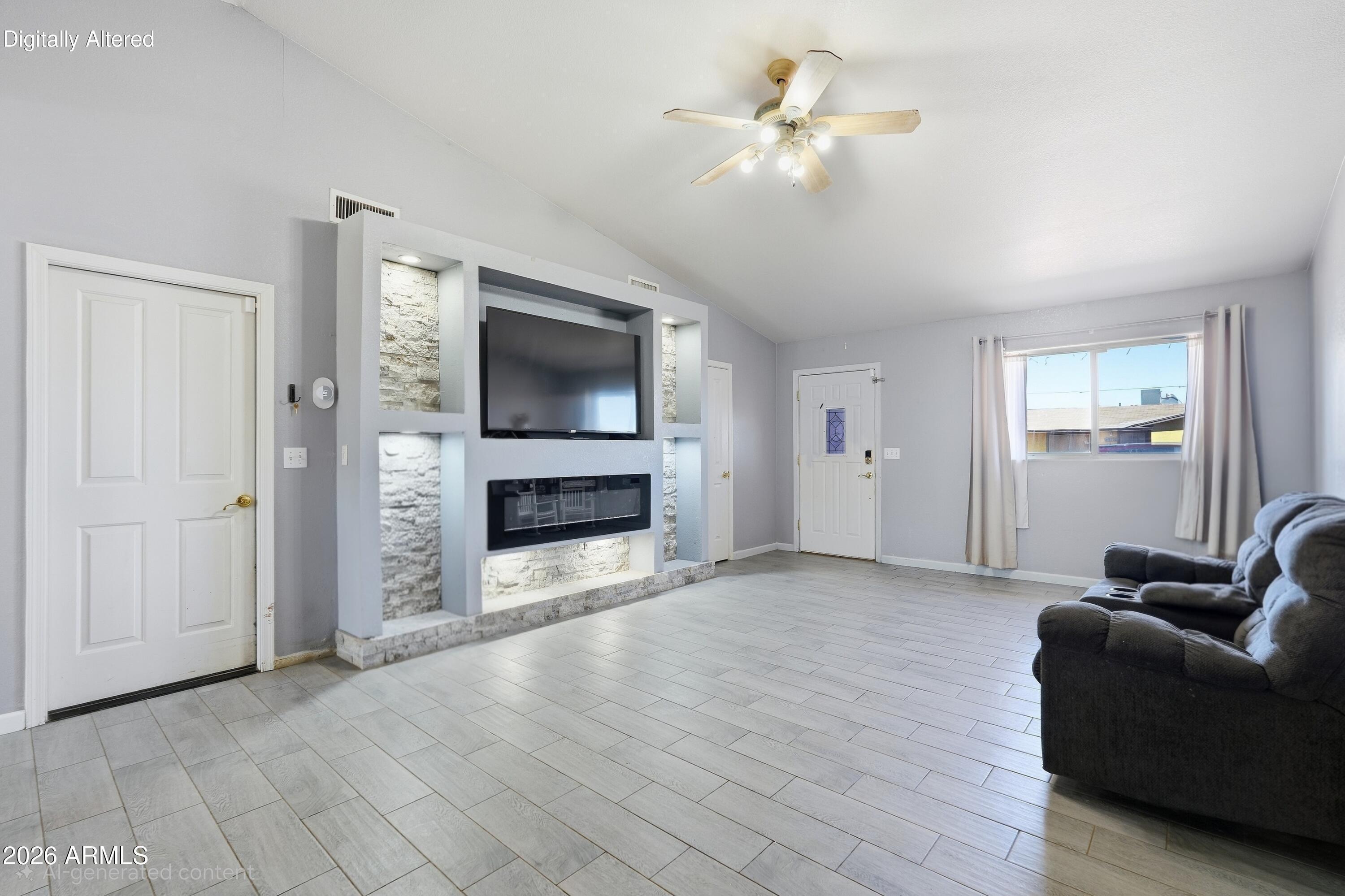 Living room with a stone-accented media wall, electric fireplace, tiled floor, and dark recliner sofa.