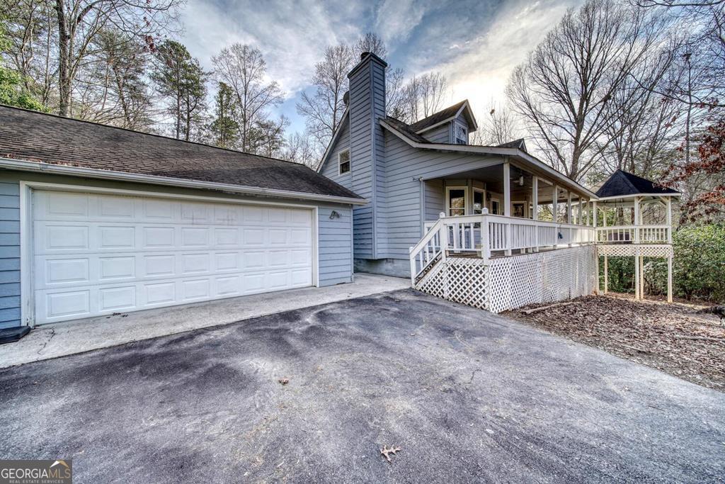 Blue-gray house with attached double garage and a long covered porch and deck.