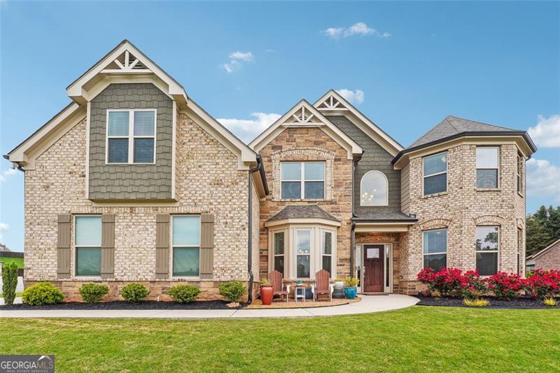 Two-story brick-and-stone home with prominent gables, a bay window, and a landscaped front lawn.