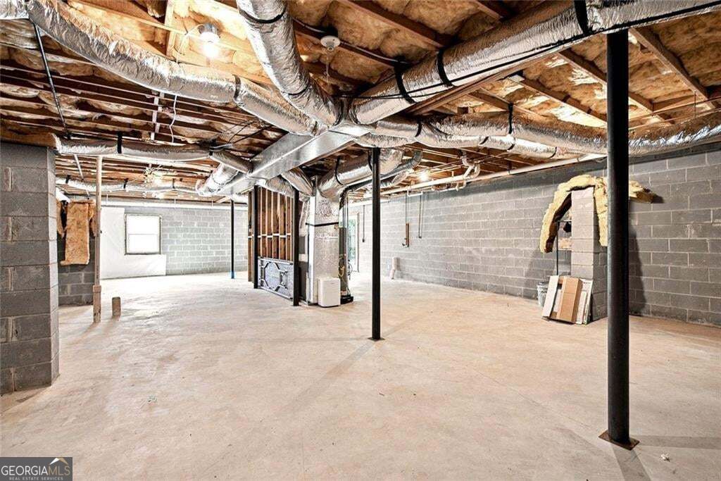 Unfinished basement with exposed ceiling joists, ductwork, concrete floor, and support posts.
