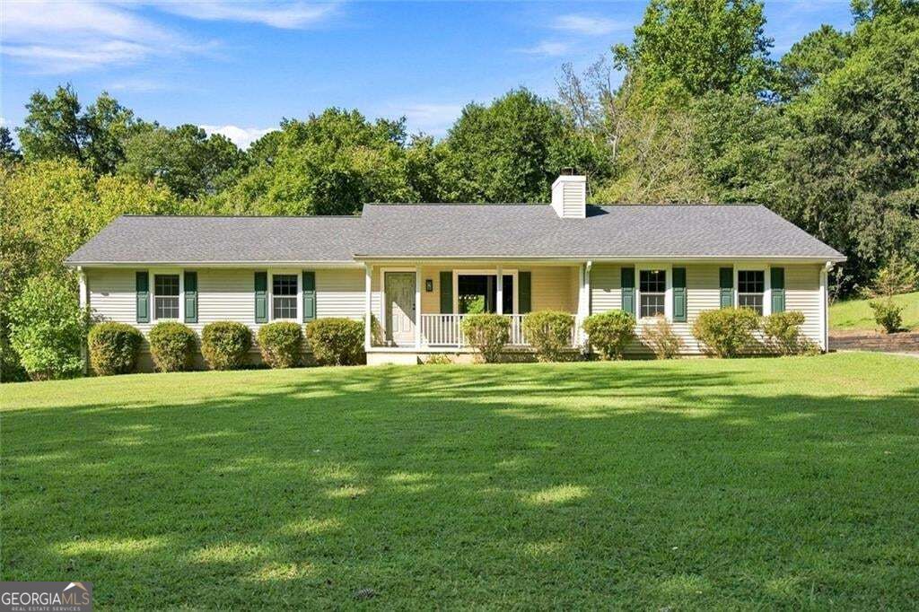 Single-story home with a covered front porch, green shutters, and a broad lawn.
