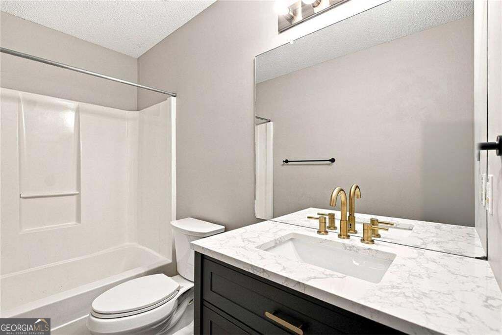 Bathroom with a tub-shower, marble vanity top, and brass fixtures.