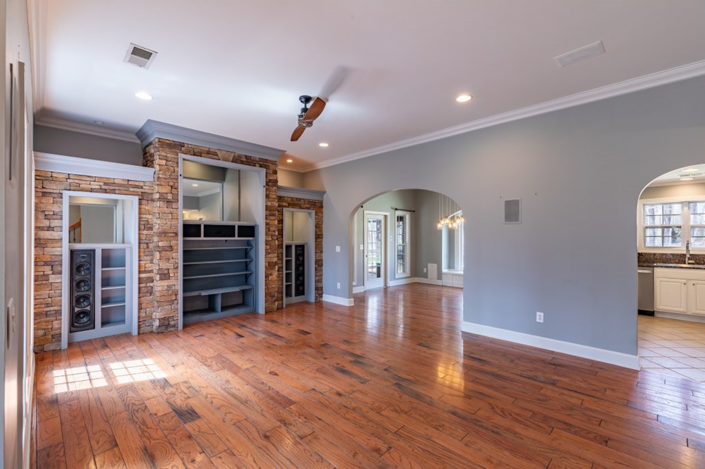 Living room with hardwood floors, a stone entertainment center, and arched openings.