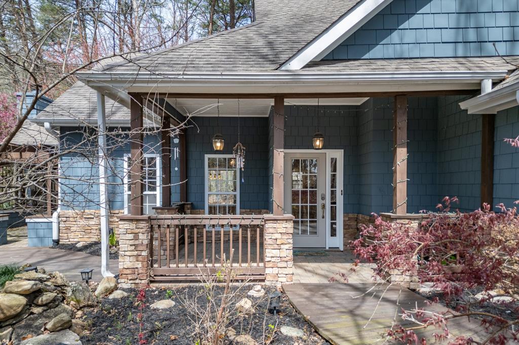Blue-shingled home with a covered porch, stone walls, and white French doors.