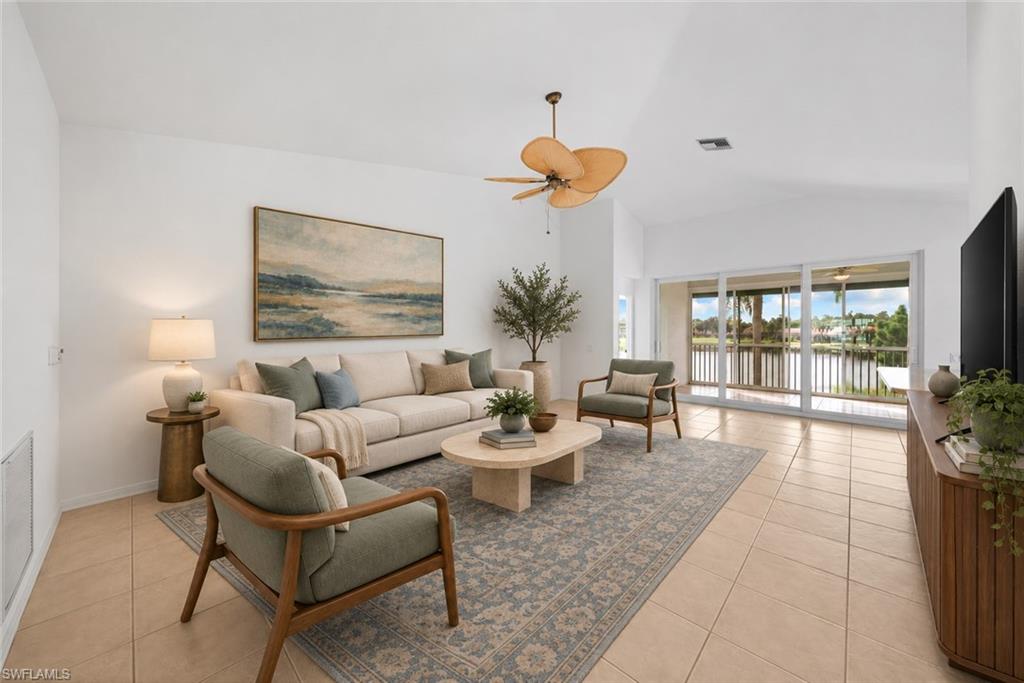 Living room with neutral seating, tiled floors, and sliding doors overlooking the water.