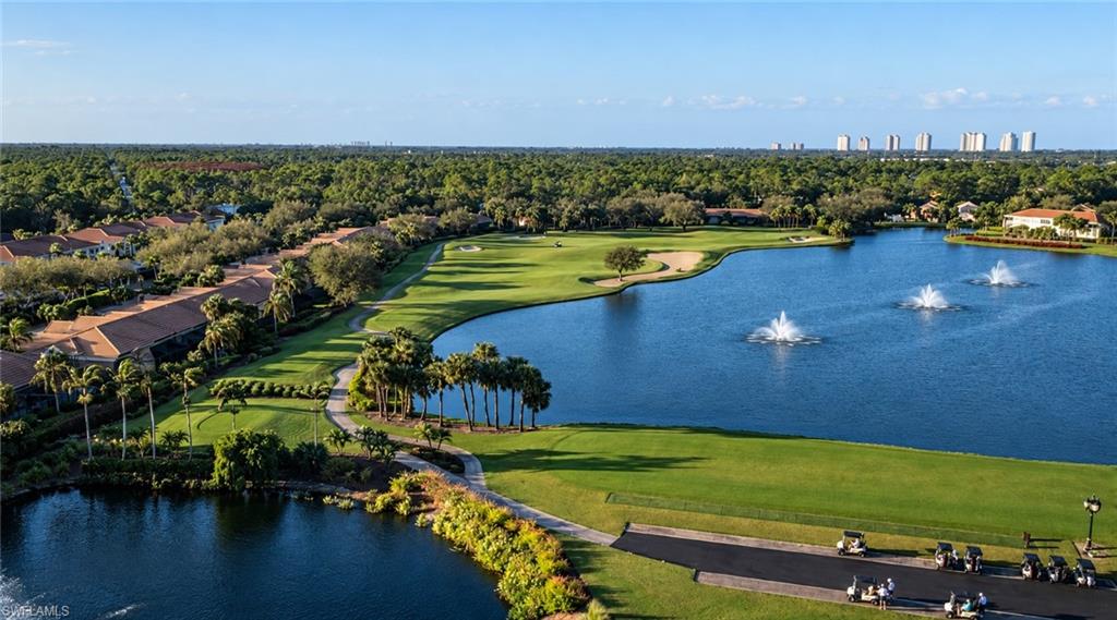 Aerial view of a golf course beside a fountain lake, homes, and fairways.