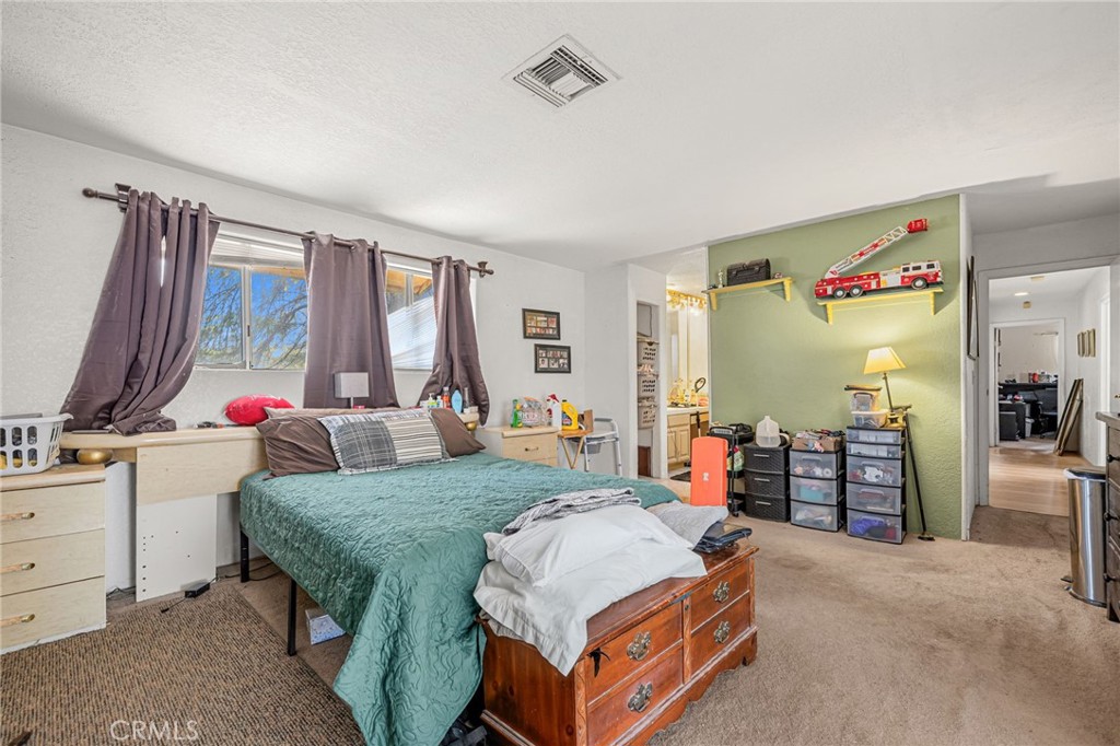 Bedroom with teal bedspread, curtained window, and green wall with toy fire trucks.