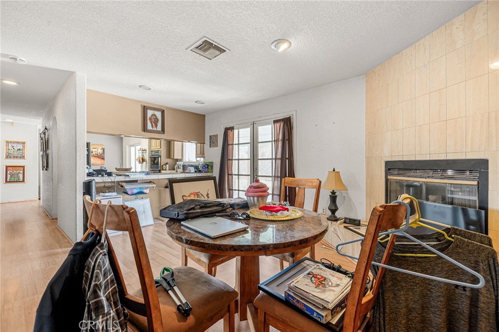 Dining area with a round table and chairs, kitchen opening, and tiled fireplace wall.